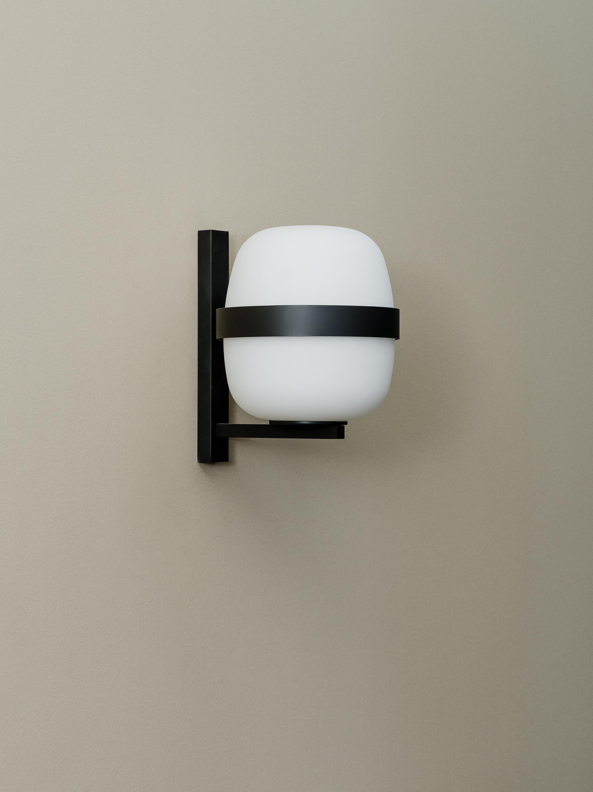 Black Wally wall lamp by Miguel Milá
Dimensions: D 18.4 x W 10 x H 24 cm
Materials: Metal, glass.
Also available in white.

In the Wally lamp, the iconic globe-shaped shade from the Cesta family is supported by a metallic ring in white or