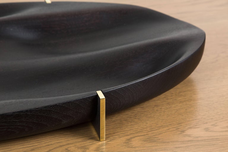 Ebonized walnut and brass oval tray by artist Vincent Pocsik in collaboration with Lawson-Fenning. Features sculptural carved wood and a machined brass base. Made of natural materials, this decorative object can be accessorized on table top, book