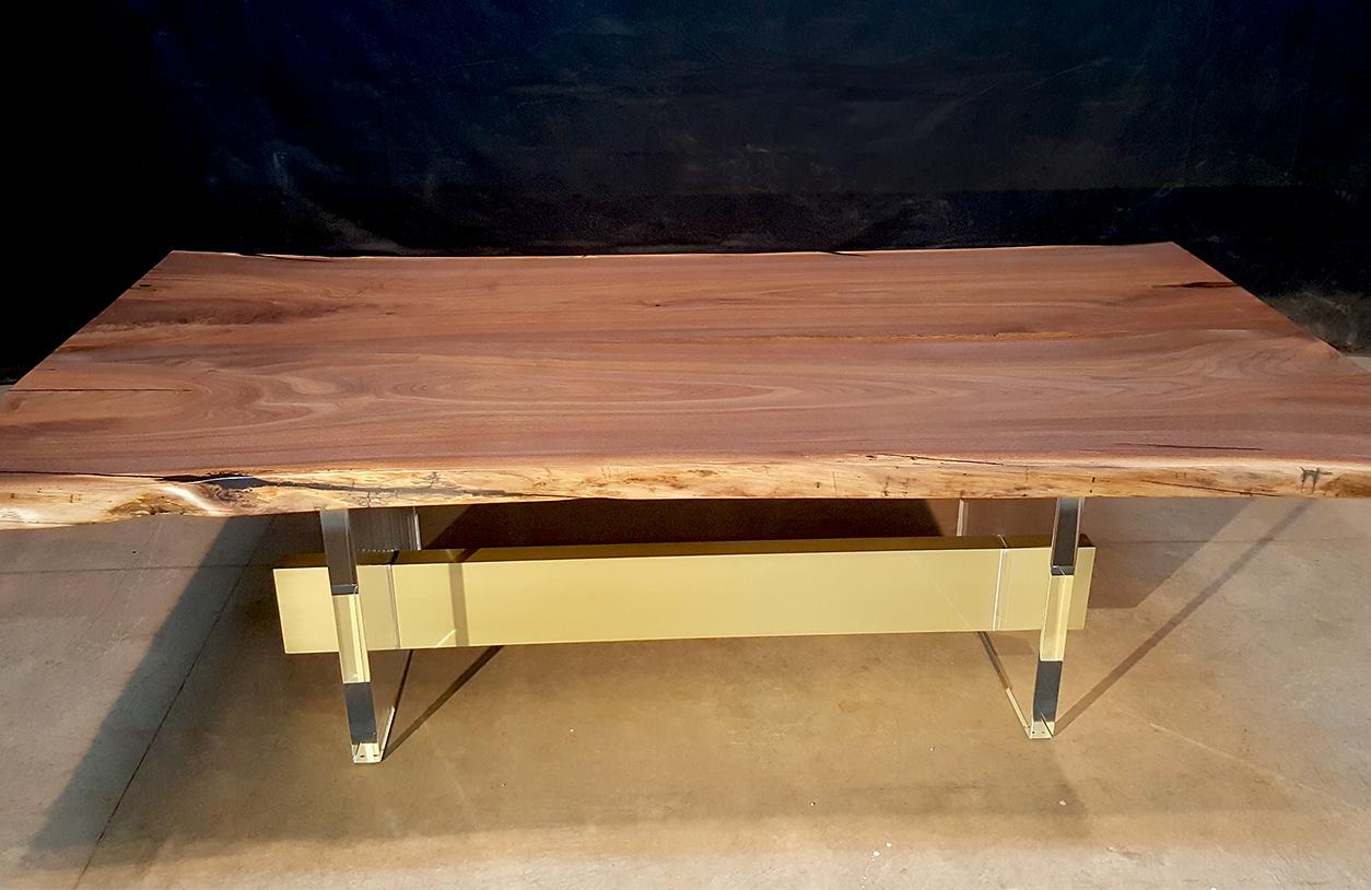 Black walnut live edge dining table with acrylic legs and bronze spandrel.
