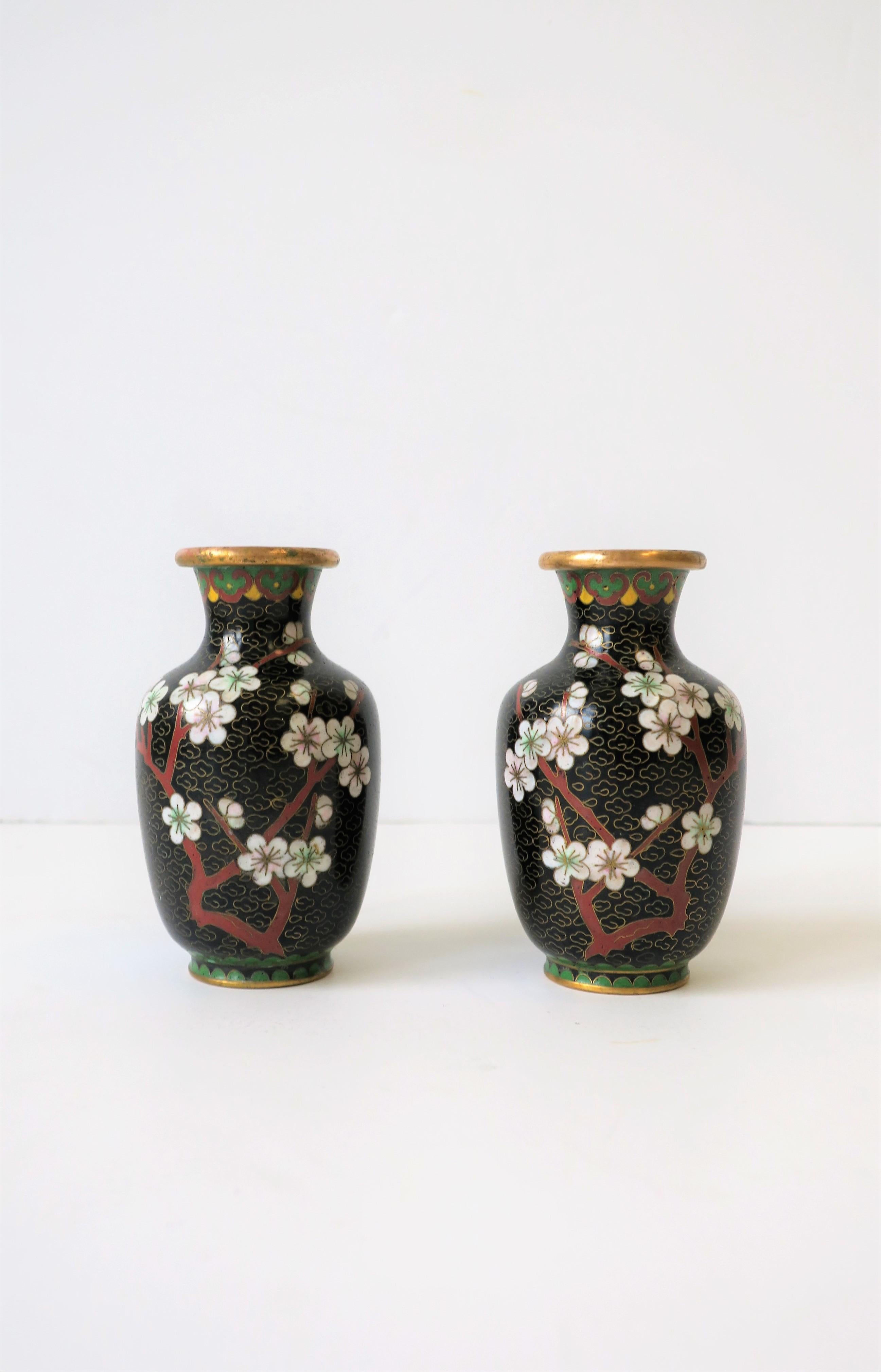 A beautiful pair of vintage gold brass and cloisonné enamel vases in black, red burgundy, and white , with a cherry blossom flower design, circa 1970s, China. Vases are predominantly black, white, and red burgundy, with touches of green and yellow