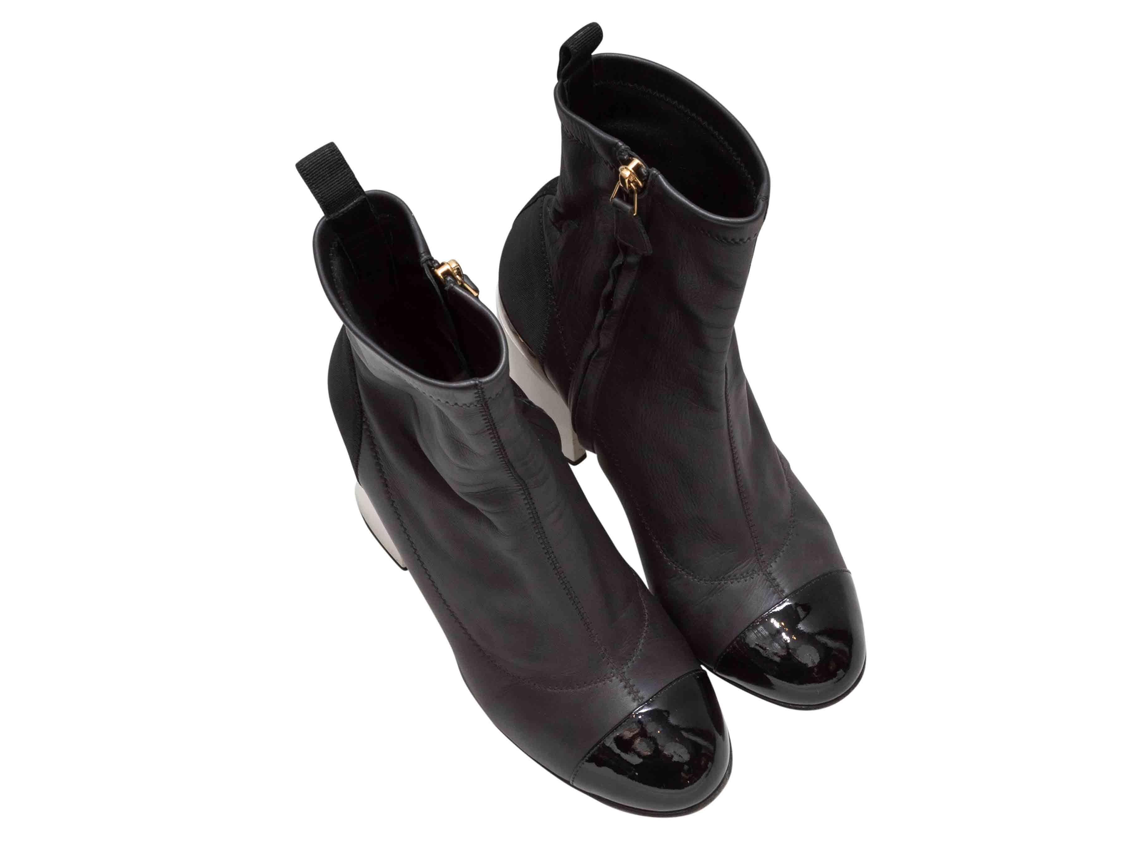 Bottines à talon en cuir noir et blanc de Chanel. Bordure en maillons de chaîne dorés aux talons. Fermeture à glissière sur les côtés intérieurs. Hauteur de la tige : 6