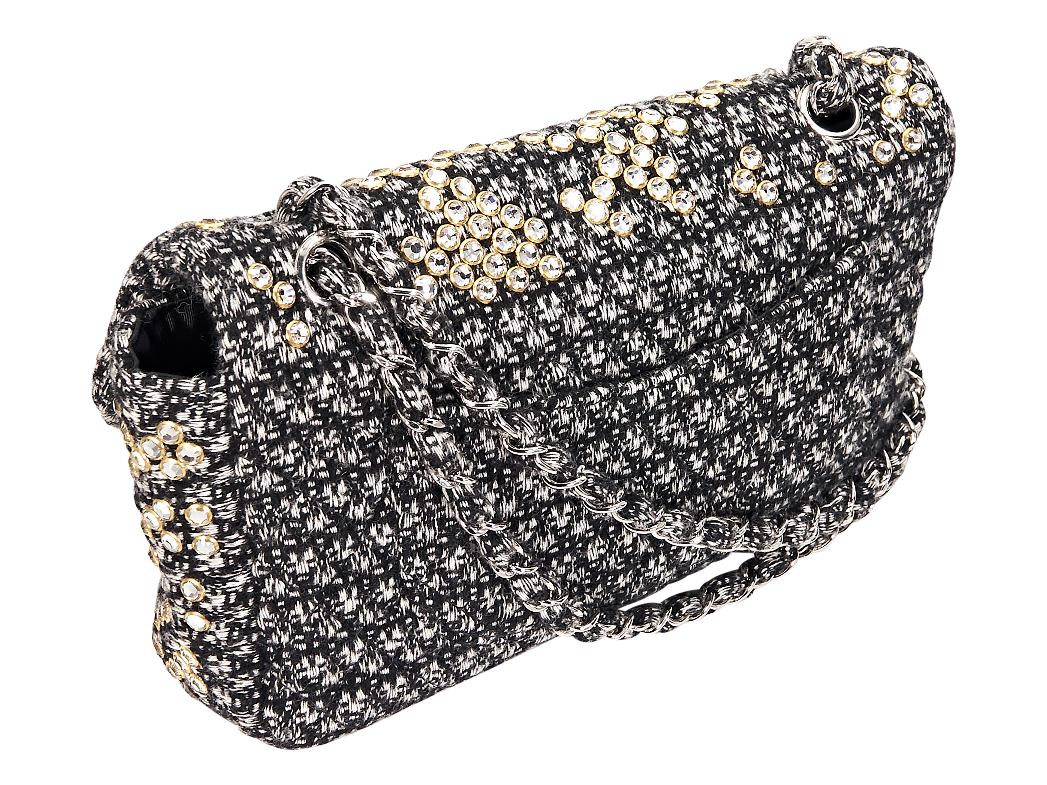 Product details:  Black and white tweed classic flap shoulder bag by Chanel.  Accented with Swarovski crystals.  Dual chain shoulder straps.  Front flap with twist-lock closure.  Lined interior with inner zip and slide pockets.  Back exterior slide