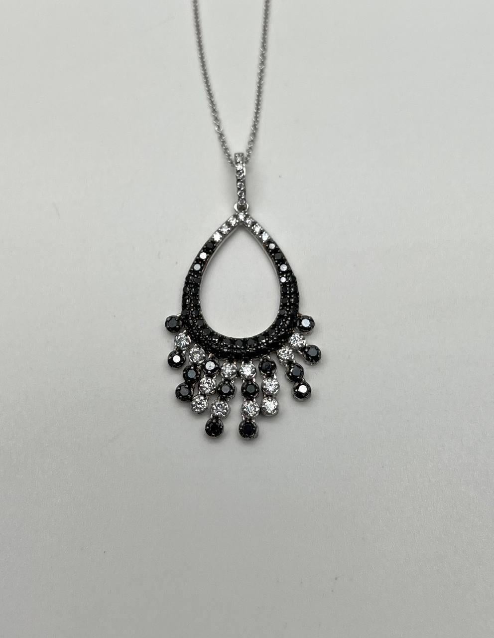 Pendant necklace featuring a teardrop design adorned with black and white stones. The upper section is encrusted with black diamonds , while the lower section showcases alternating black and white diamonds in a cascading pattern. 14K White Gold.