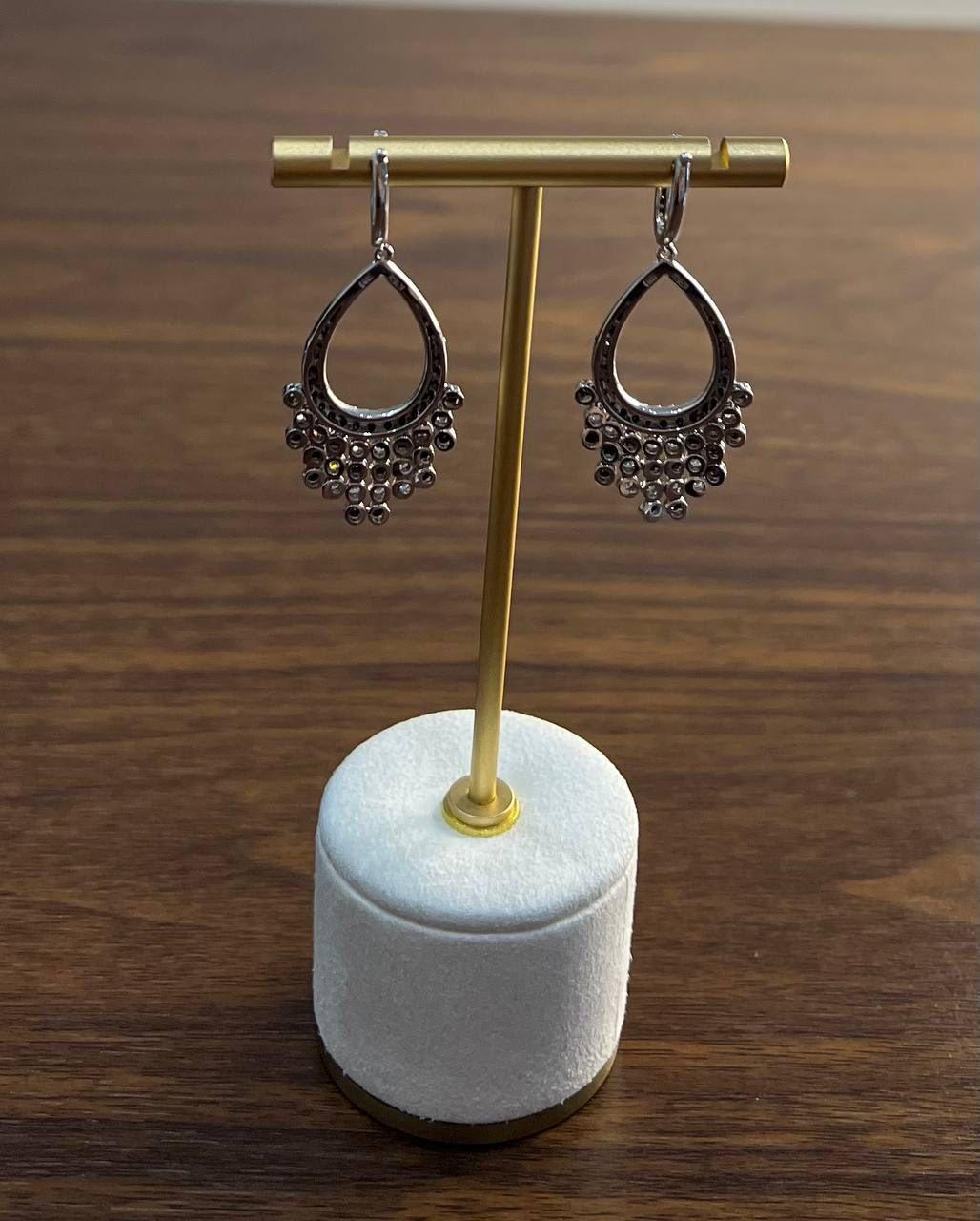 These striking earrings are crafted in a combination of 14k gold and white gold. Each earring features a teardrop design adorned with black diamonds, totaling 2.93 carats, set in a pave style. The black diamonds are complemented by a row of white