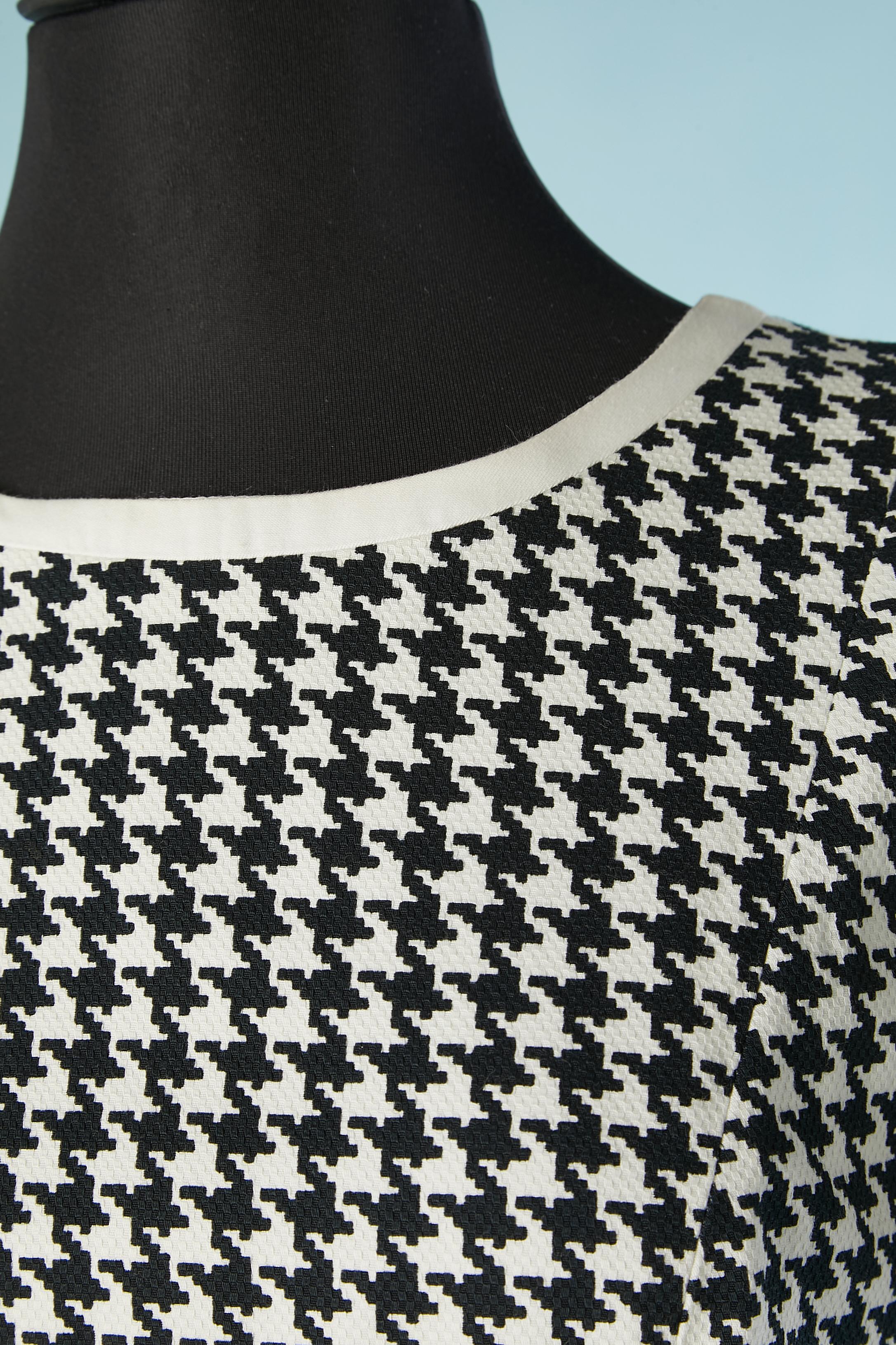 Schwarz-weißes Kleid mit Hahnentrittmuster. Stoff:100% Baumwolle. Innenfutter: 100% Polyester. Reißverschluss in der hinteren Mitte. Paspel am Kragen und am Ärmelrand. Schlitz in der Seite hinten, Länge: 26 cm
