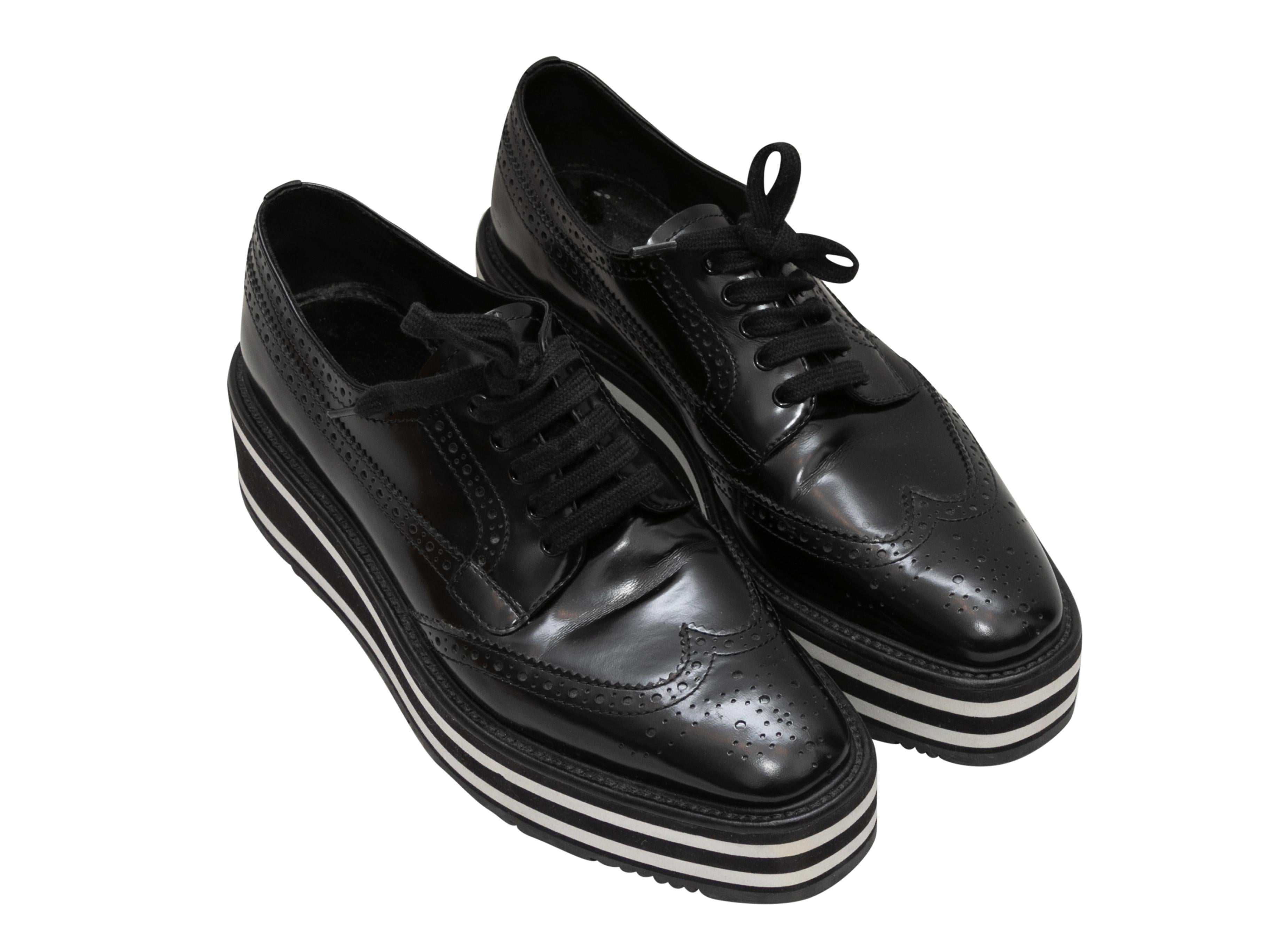 Black and white leather platform brogues by Prada. Foam rubber soles. Lace-up tie closures at tops. 1.5
