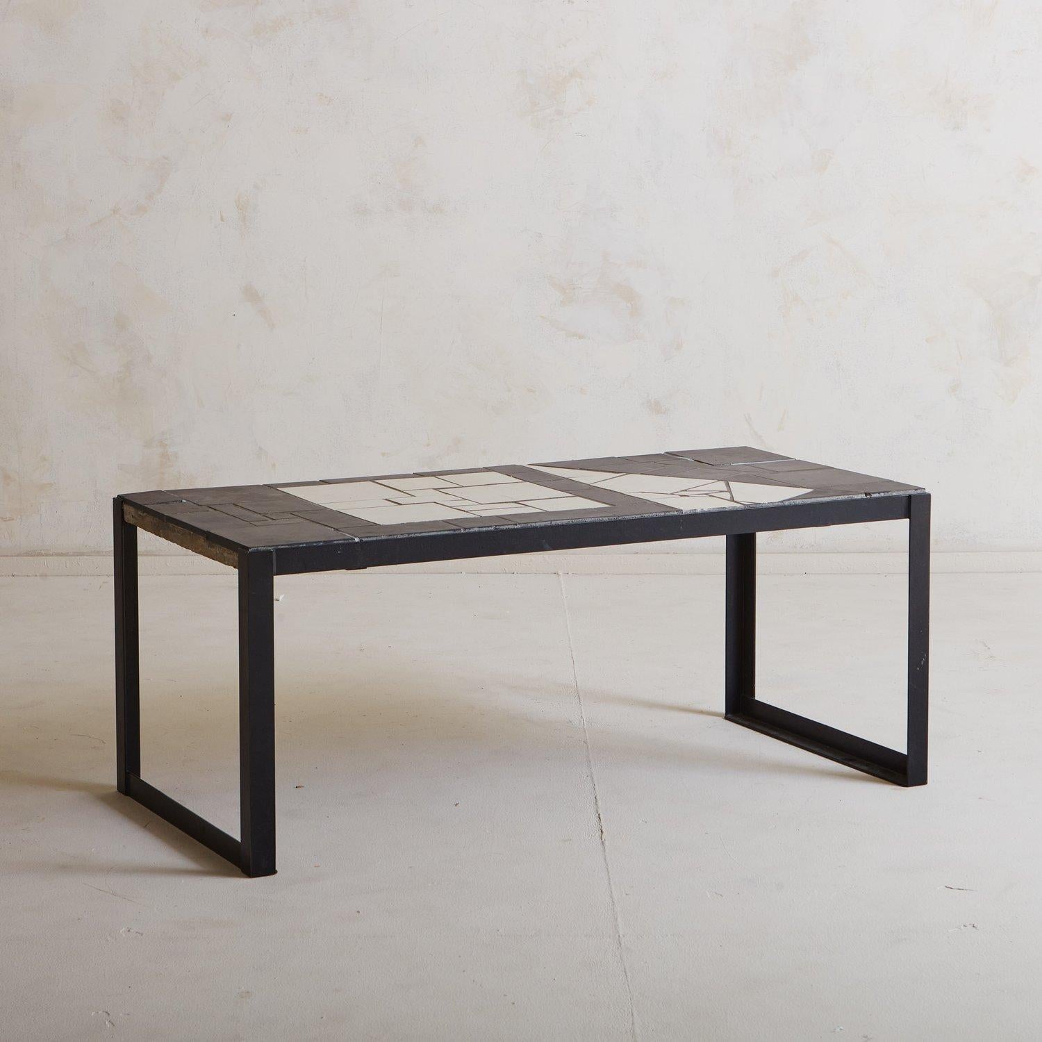 A vintage Swiss coffee table featuring an abstract black and white tiled top. This table stands on angular black metal legs. Sourced in France, 20th Century.

