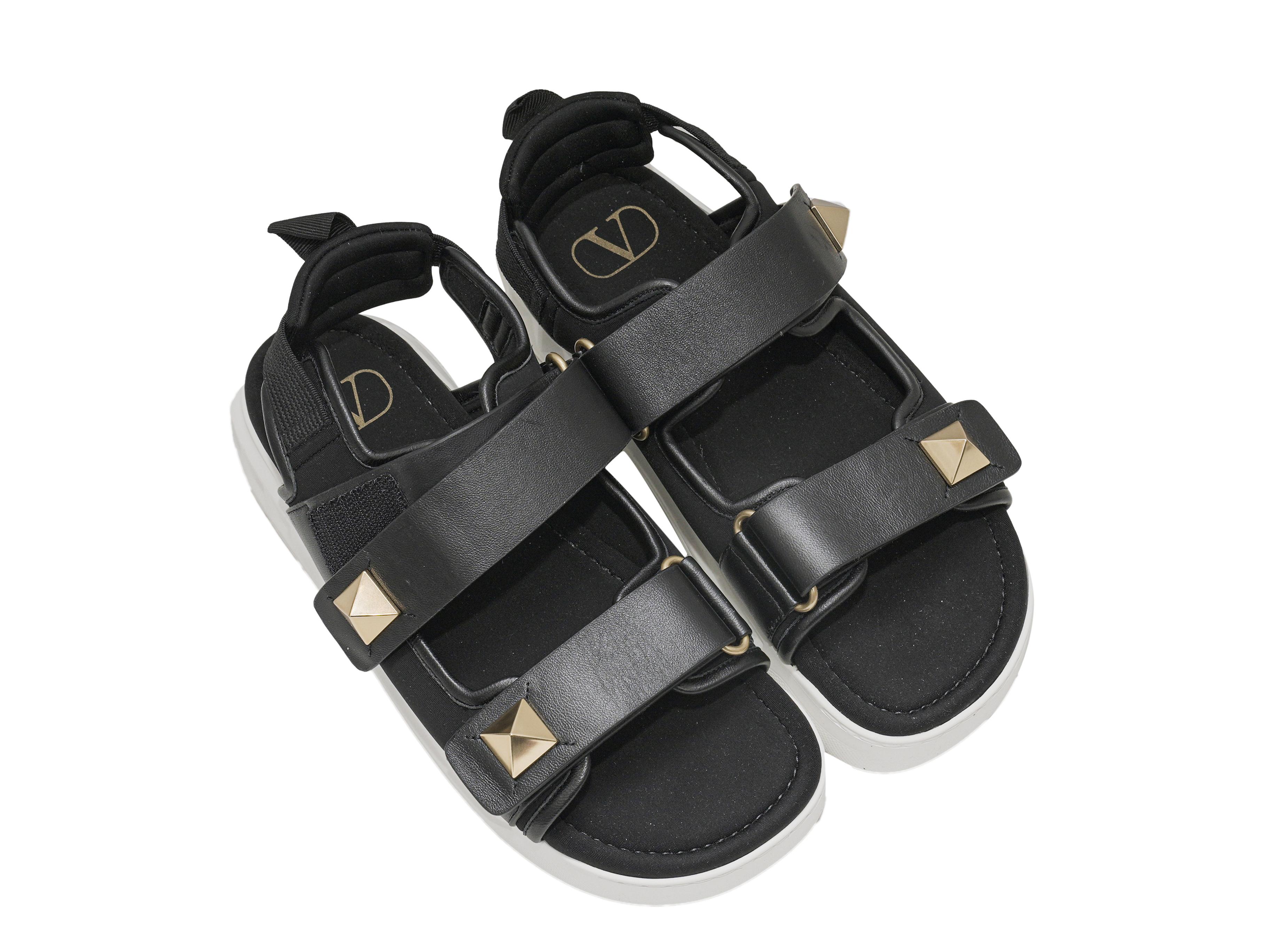 Sandali Rockstud in pelle nera e gomma bianca di Valentino. Chiusura con cinturino in velcro. Altezza plateau 1