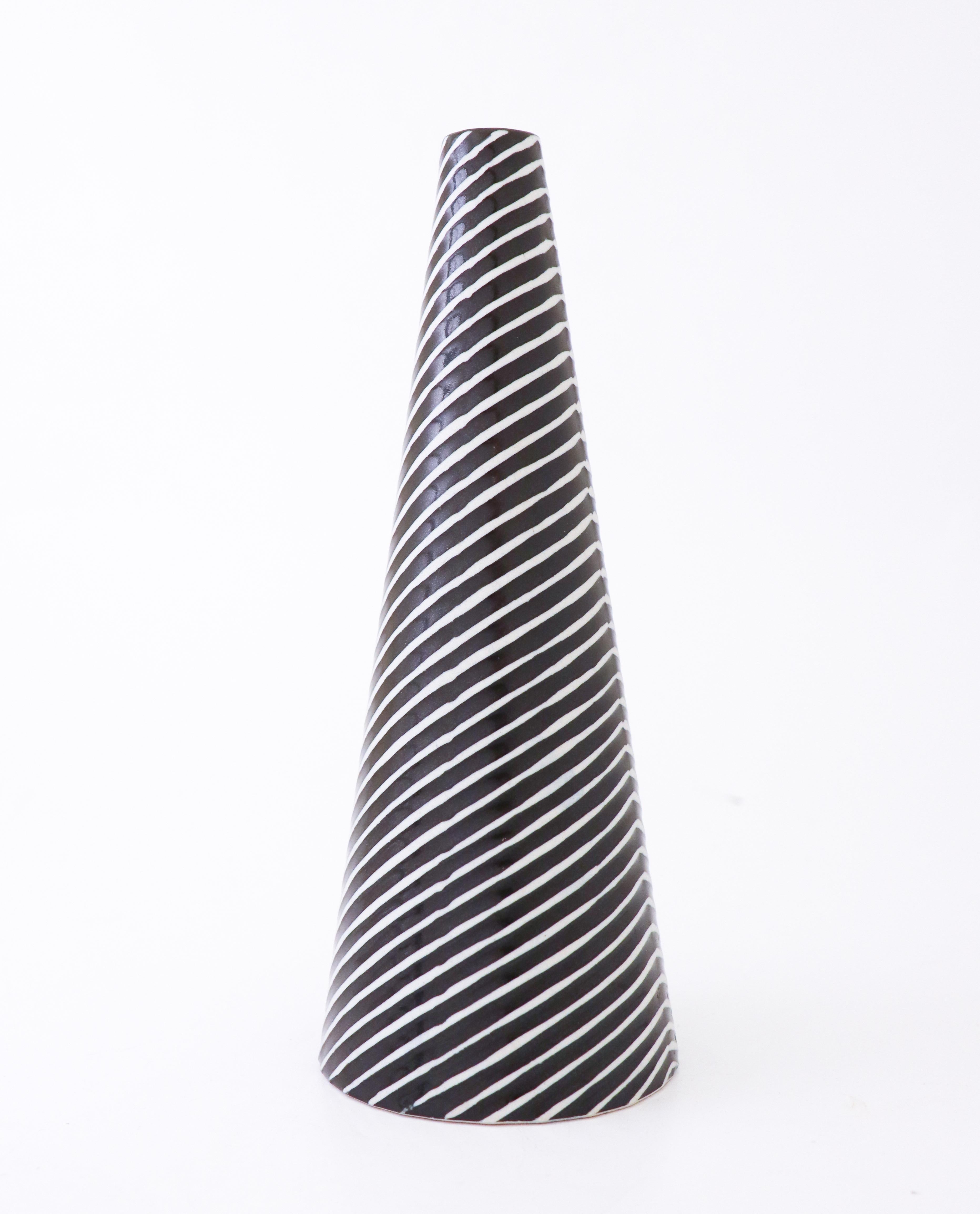 A lovely vase designed by Stig Lindberg at Gustavsberg. It is 23,5 cm high and 9 cm in diameter and have a lovely glaze. It is in very good condition except from a minor mark at the lower rim from the production. 

The Domino serie was created by