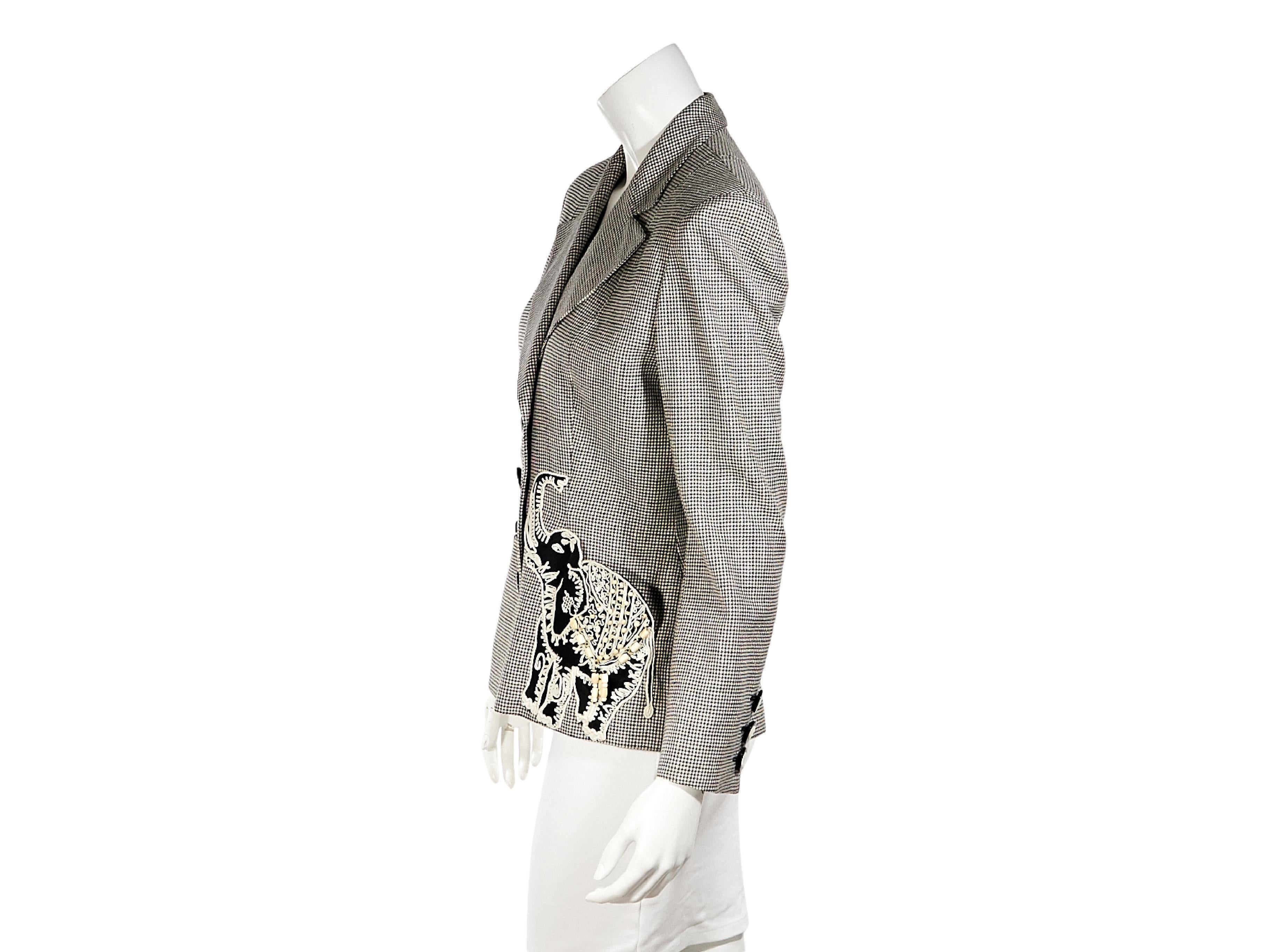 Product details:  Vintage black and white wool houndstooth blazer by Valentino.  Circa the 1980s.  Peak lapel.  Long sleeves.  Three-button detail at cuffs.  Button-front closure.  Waist patch pockets with elephant applique design.  36