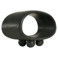 Scultura in ceramica cava con piedi a sfera, costruita a mano, di colore nero con sfumature verde scuro.