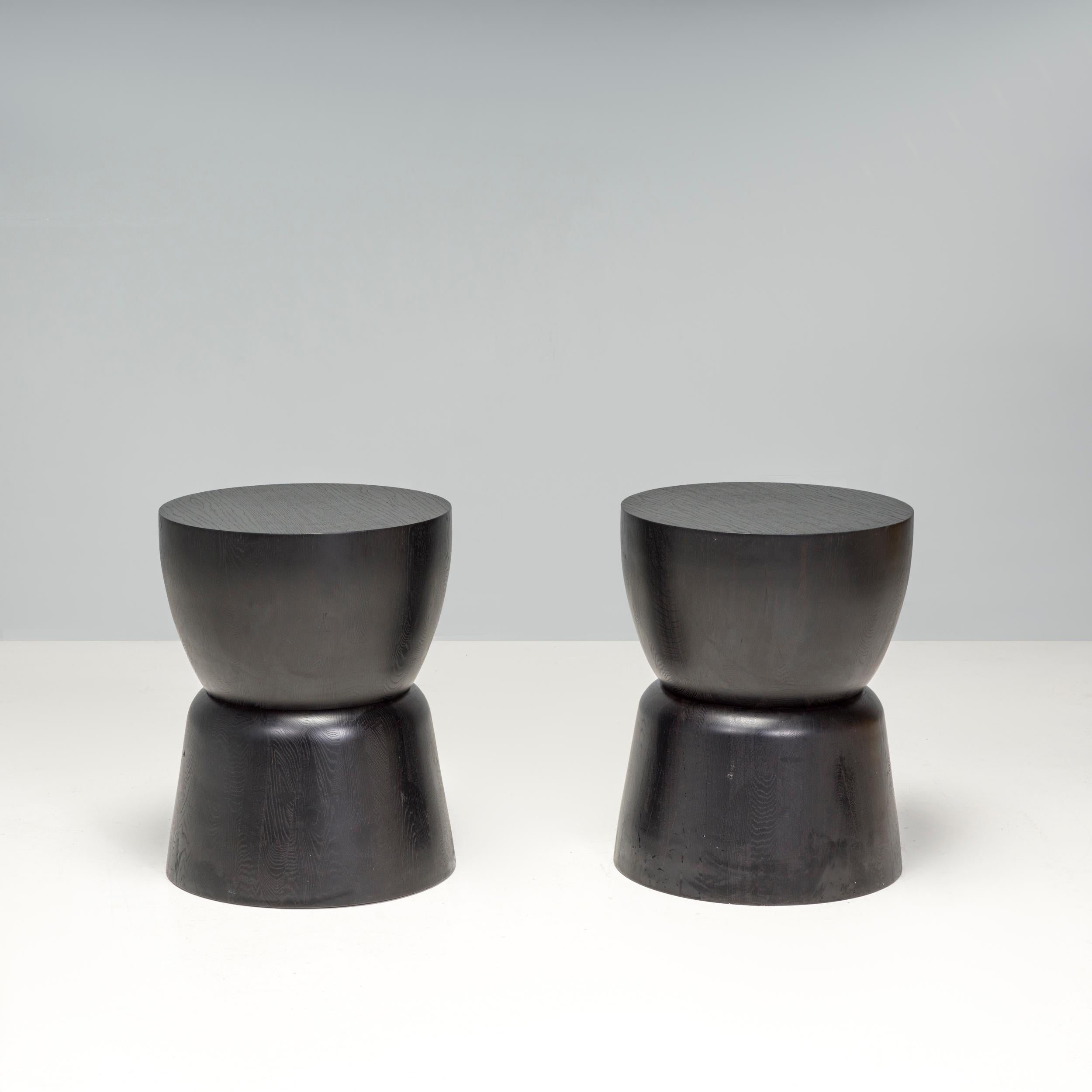 Simple yet chic, this pair of drum shaped side tables are sculptural pedestal statement pieces. 
 
Carved from a solid block of wood and stained black, the side tables have a flat circular top and a curved drum shaped body. Can be used as a pair of