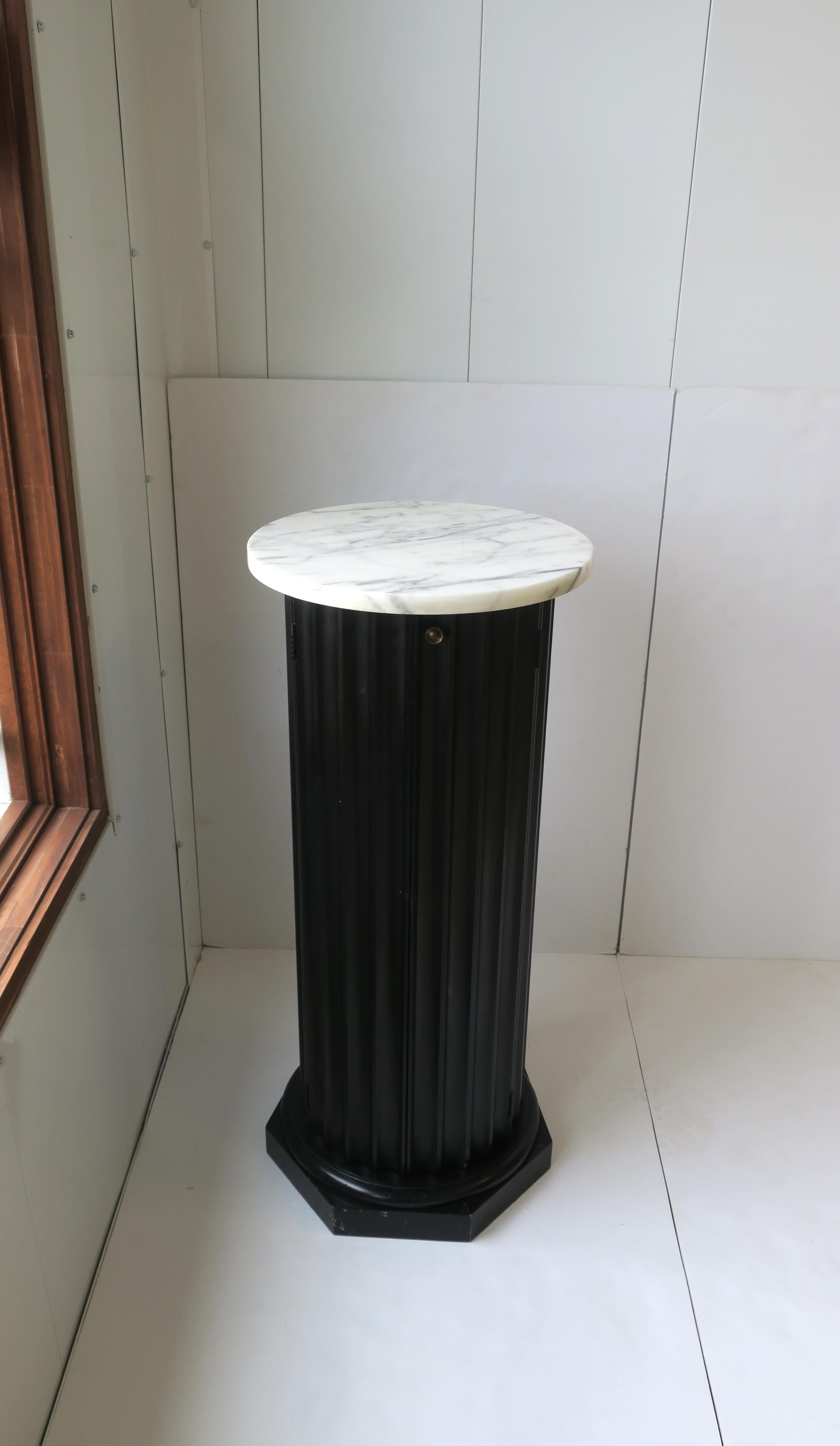 **Two available, each sold separately, as per listing

A beautiful black fluted wood and white marble top pillar column pedestal stand in the Neoclassical design style, circa mid to late-20th century. Fluted wood pedestal is black with a white