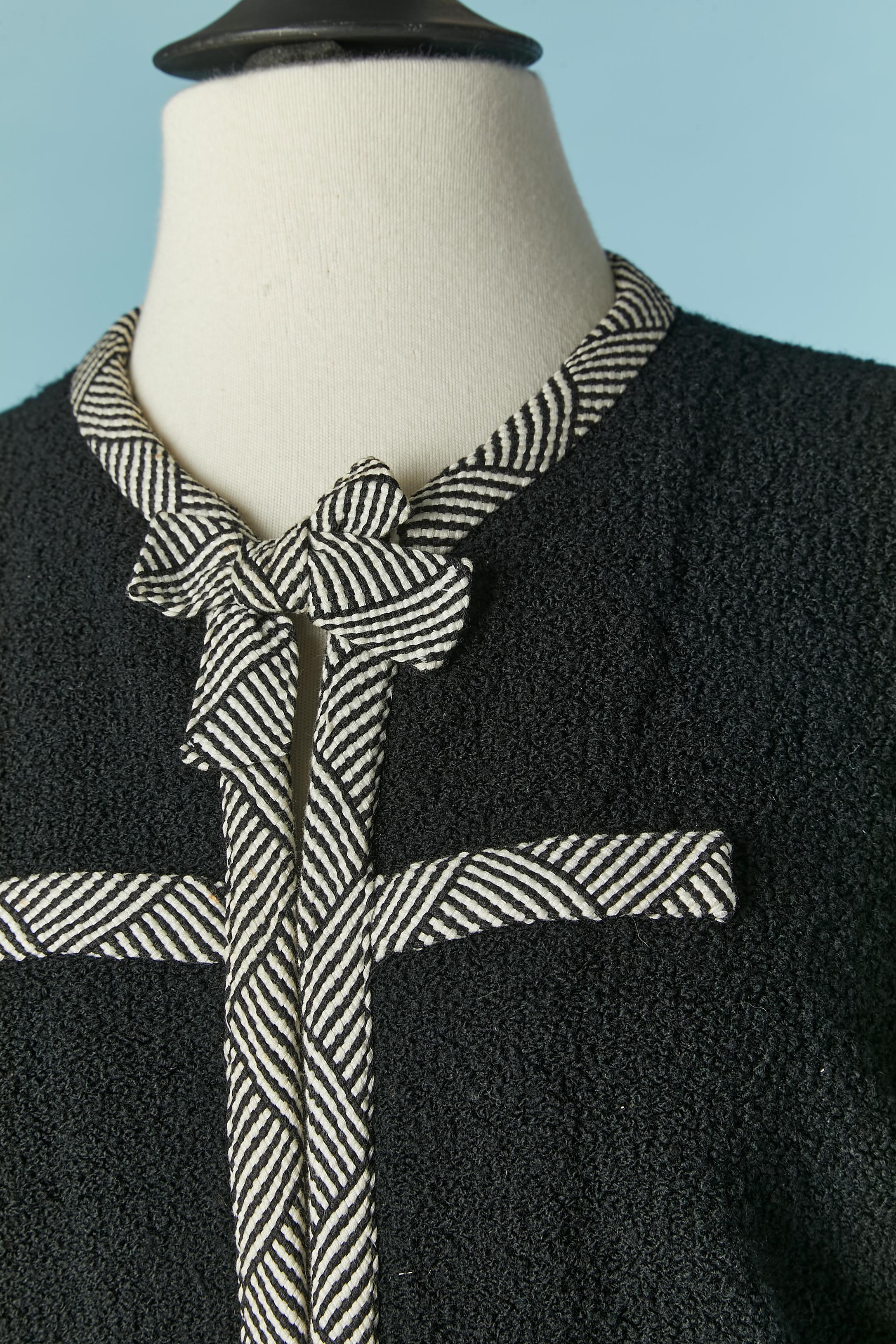 Black wool bouclette skirt-suit with black&white braid piping and bow. Hook&eye closure on the middle front. 
Thin shoulder pad made of knit.
SIZE L 
