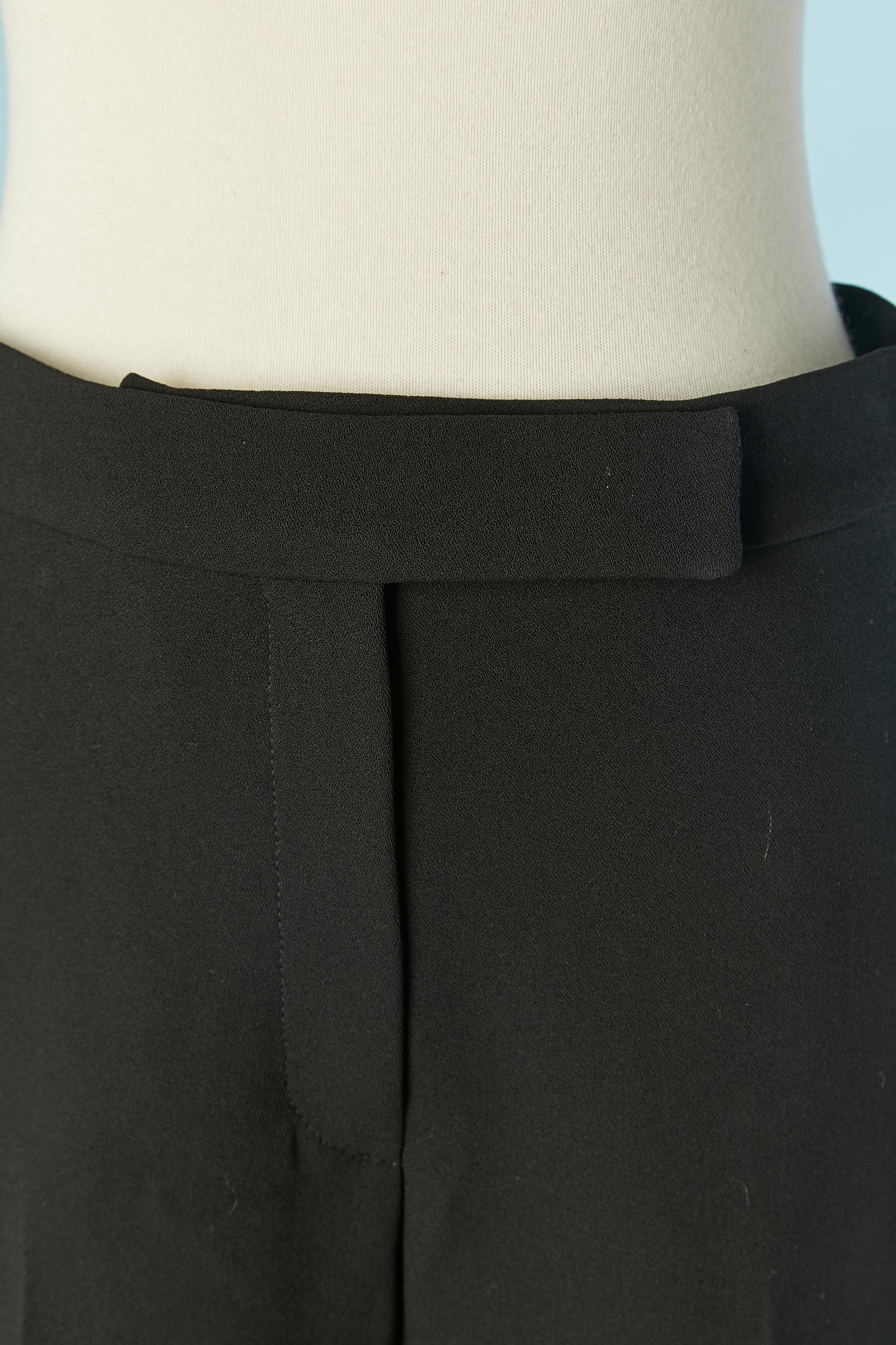 Pantalon en crêpe de laine noir avec revers inférieur. Fermeture zippée avec tirette zippée de marque sur le milieu du devant + crochet et œillet. Pas de doublure. 
Pochette au dos. 
TAILLE 38 (Fr) M 