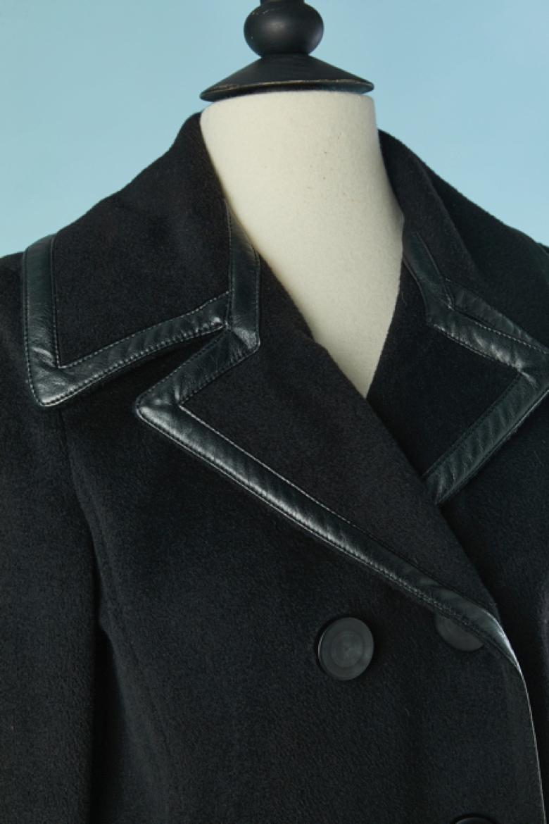 Cappotto doppiopetto in lana nera con profili in pelle. Composizione del tessuto principale: 90% lana, 7% nylon, 3% poliuretano. Fodera in seta. 
Spallaccio. Tasca su entrambi i lati.
TAGLIA 42 