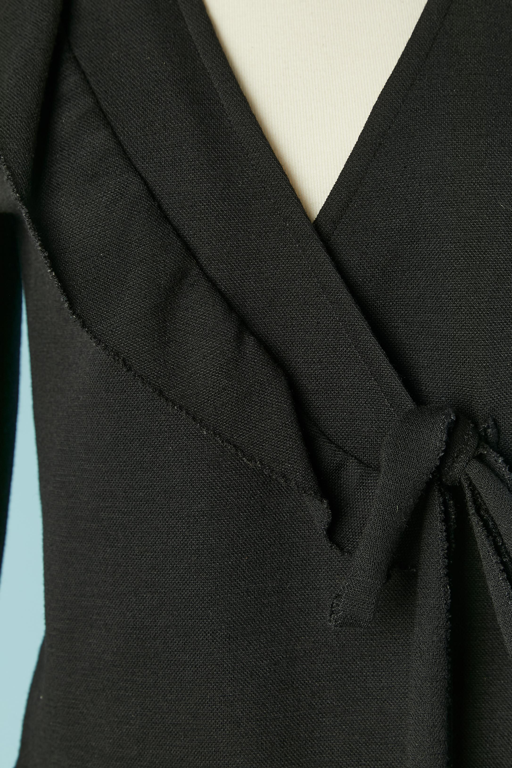 Black wool jersey skirt-suit with ruffle. Shoulder-pad. Links to tie on the middle front outside and inside + button and buttonhole closure. 
SIZE of the jacket : 38 (Fr) M 
SIZE of the skirt : 34/36 (Fr) XS/S 