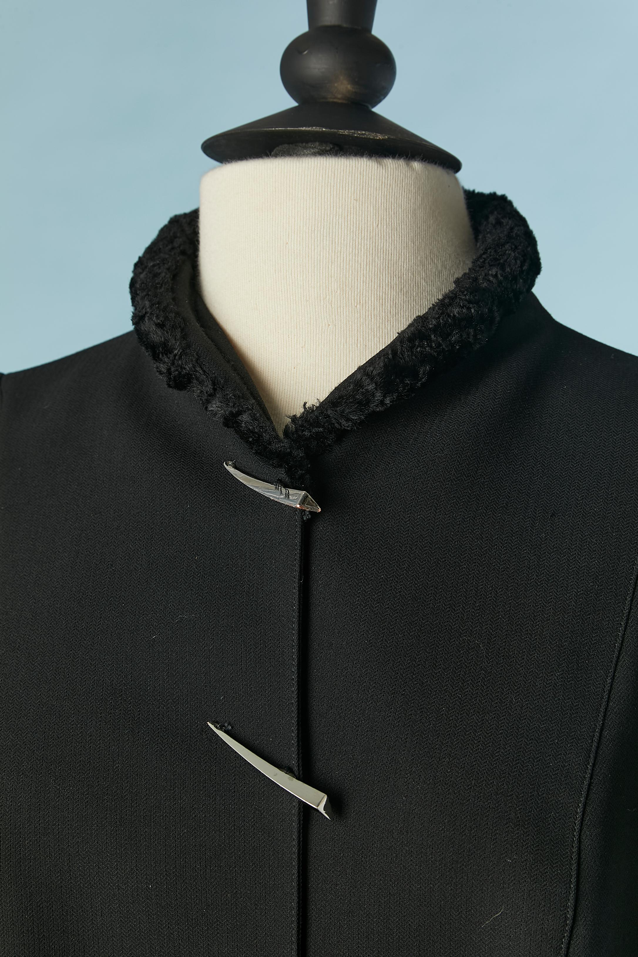 Veste en laine noire à simple boutonnage avec bord en faux-astrakan et ornementation de griffes argentées sur le milieu du devant. Structure d'épaule 