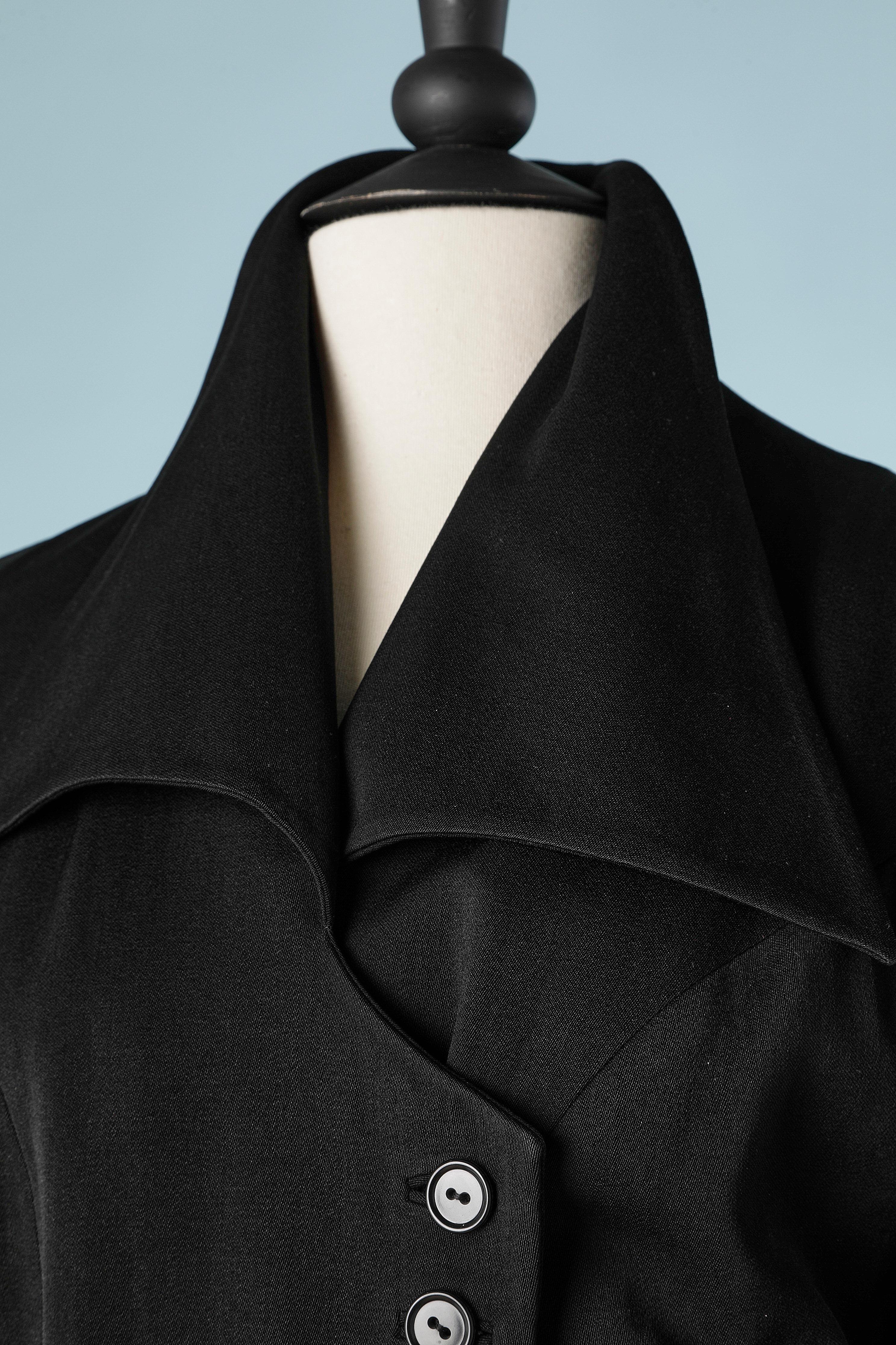 Combinaison jupe en laine noire et veste drapée à double boutonnage. Bouton-pression à l'intérieur pour le garder à portée de main. Bouton et boutonnière  sur les poignets et derrière la nuque sur le col. Doublure en rayonne ou acétate marron.