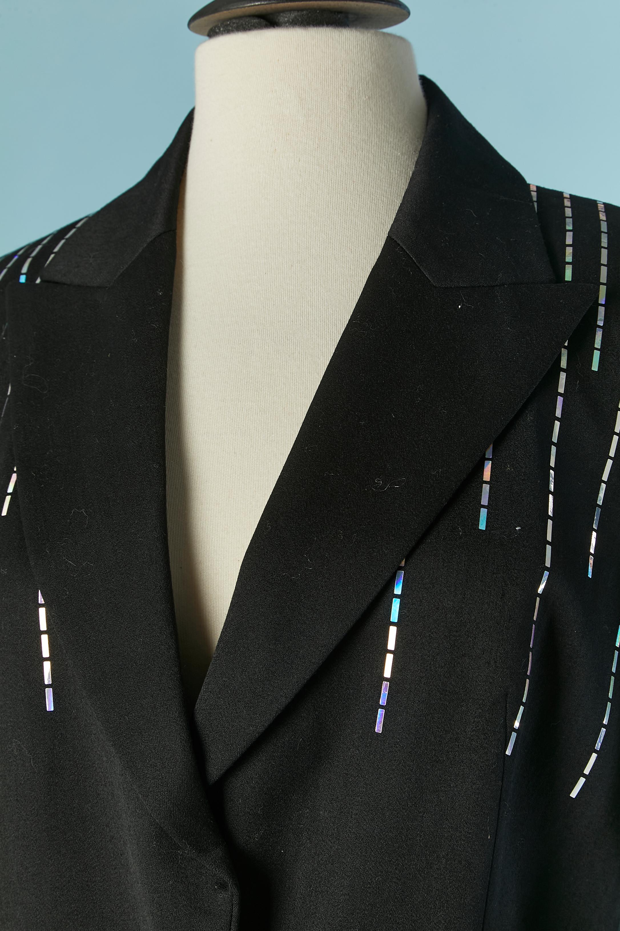 Black wool trouser pant suit with shiny plastic embellishment . Lining composition: rayon and acetate.
Shoulder pad. Hidden snap closure on the middle front. Pocket on both side on the jacket 
SIZE 40 (Fr) 12 (US) L 