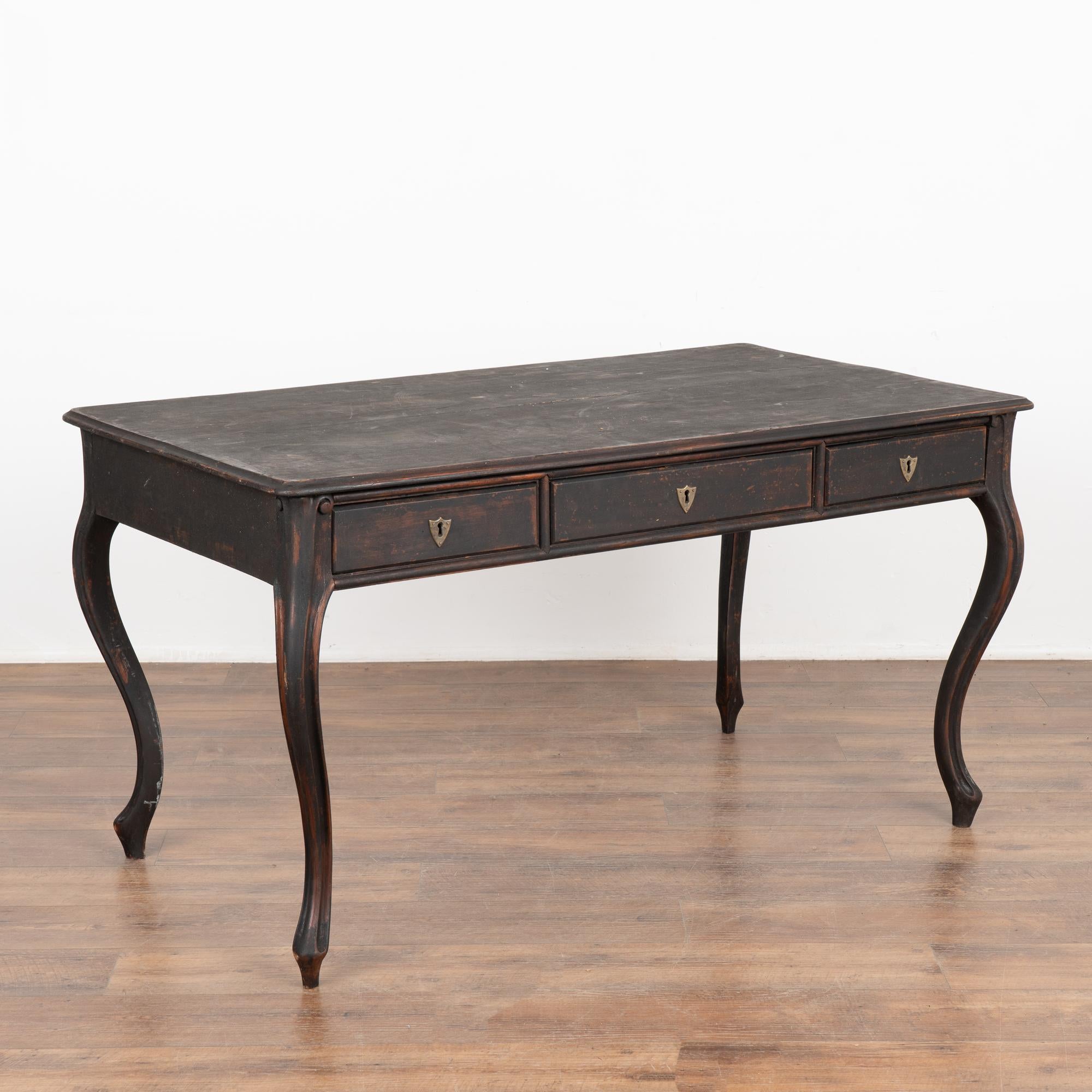 Three drawer pine desk with elongated cabriolet legs. 
Restored, later custom black painted finish which is lightly distressed to fit the age and grace of this lovely writing table. 
The old locks on each of the three drawers still function with one