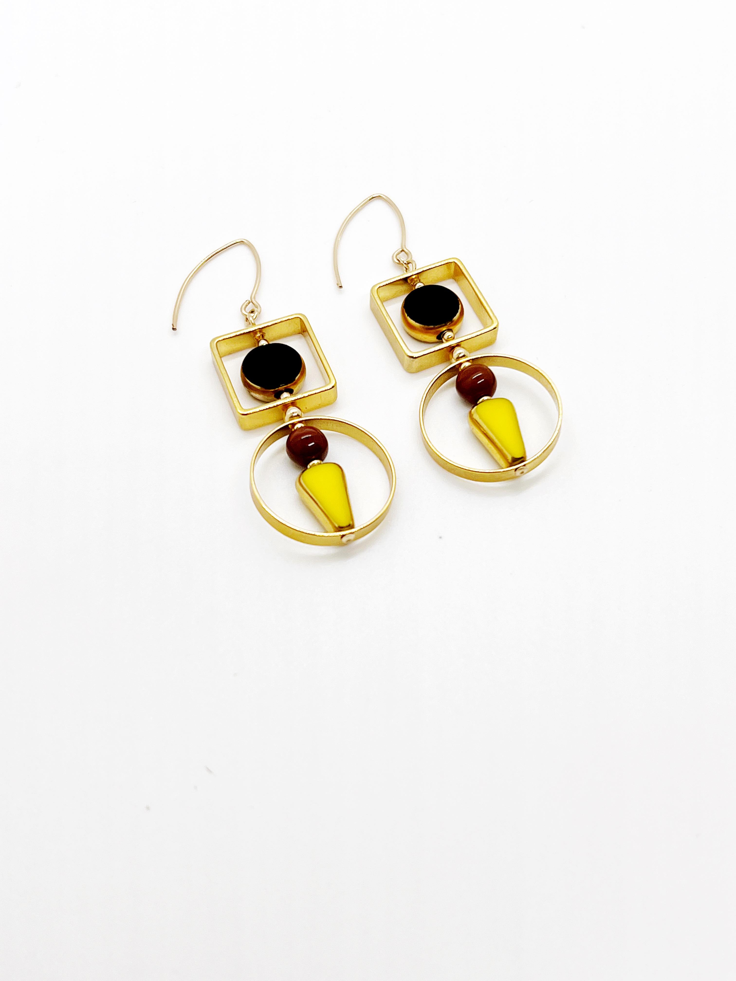 The earrings are light weight and are made to rotate and reposition with movement.

The earrings consist of a black circle and yellow triangle shaped beads. They are new old stock vintage German glass beads that are framed with 24K gold. The beads