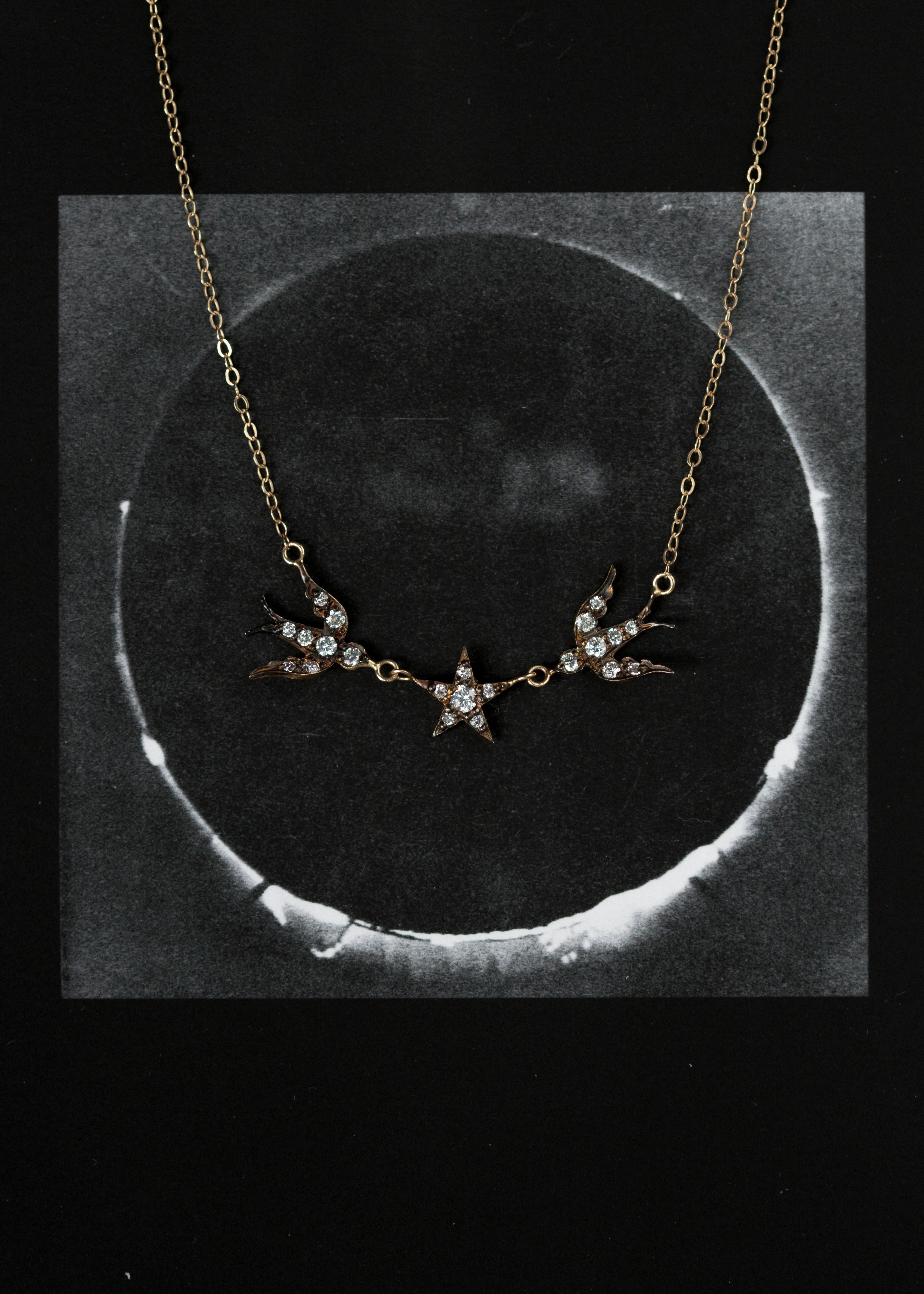 Victorian inspired swallows meet at the stars to create this whimsical BIRD STAR NECKLACE. Cast in 14k yellow gold, antique plated and set with brilliant cut diamonds. The delicate charms hang on a 16-18