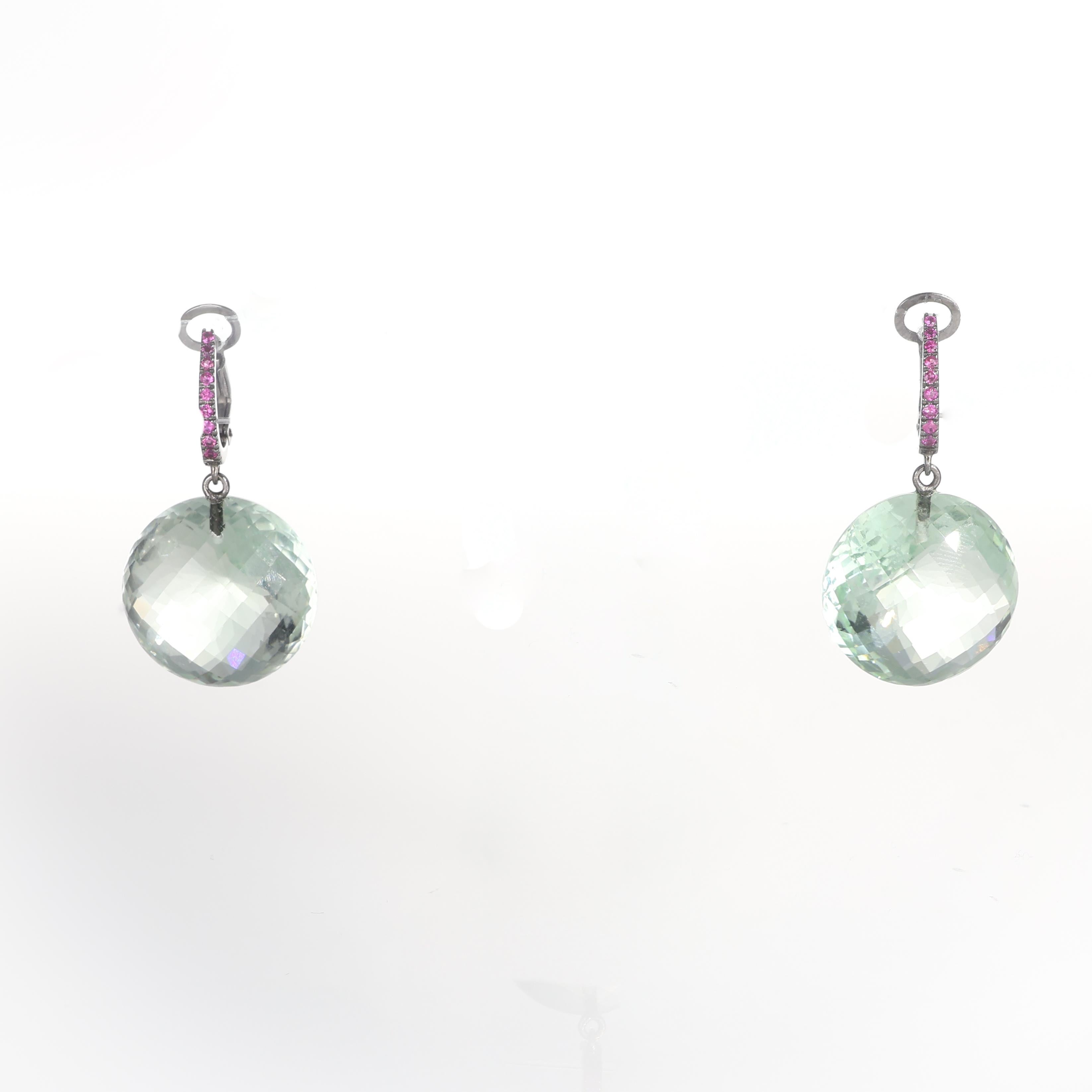 Sophisticated and modern, these earrings are crafted in blackened 18K white gold, featuring a delicate row of rubies set along the hoop for a subtle yet striking contrast. The design is completed with a dangling briolette-cut quartz, offering a
