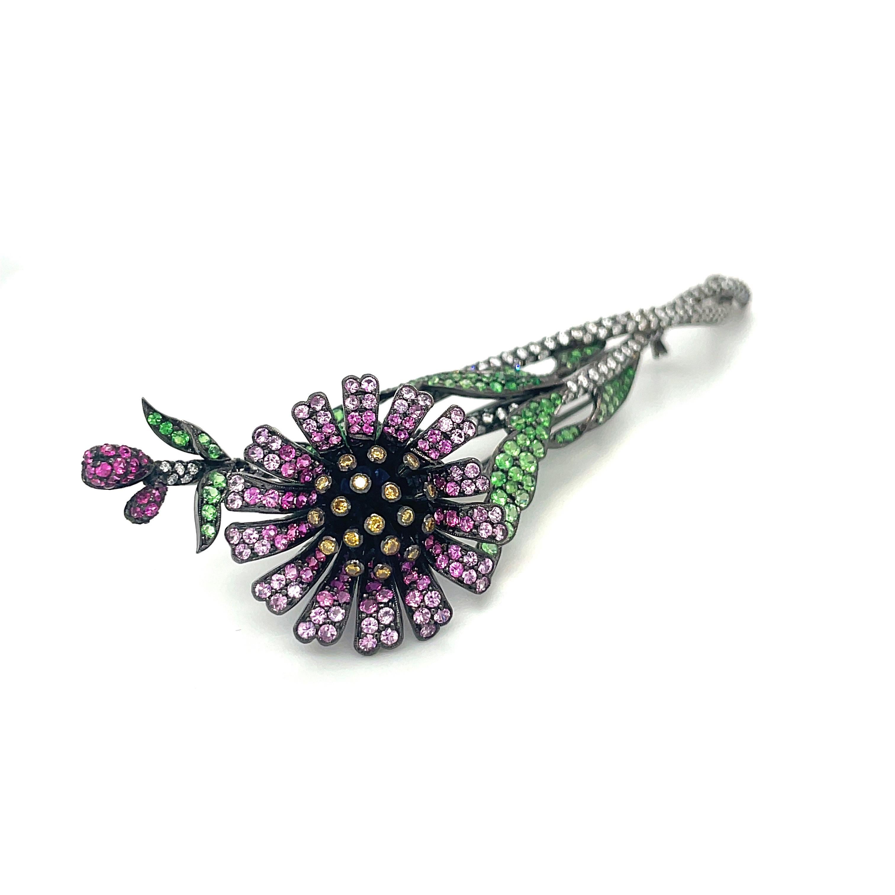 This stunning flower brooch composed of various shade of pink sapphires and tsavorites which pop against the dramatic blackened 18kt gold. Truly a work of art, this magnificent piece has 3.35cts of white diamonds, 0.24cts of yellow diamonds, 2.20