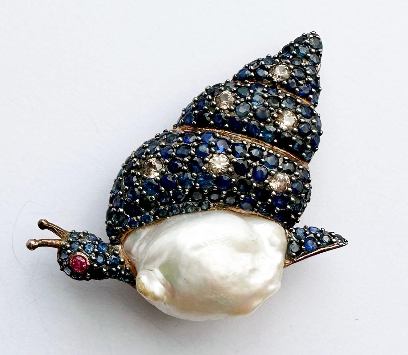 A Blackened and Rose Gold Plated, Silver Snail Brooch/Pendant set with Sapphire, Ruby, Zircon and South Sea Pearl. This brooch is also a pendant with a fold down loop bail. Plated in blackened Silver and Rose Gold, the snail's shell is a lovely pave