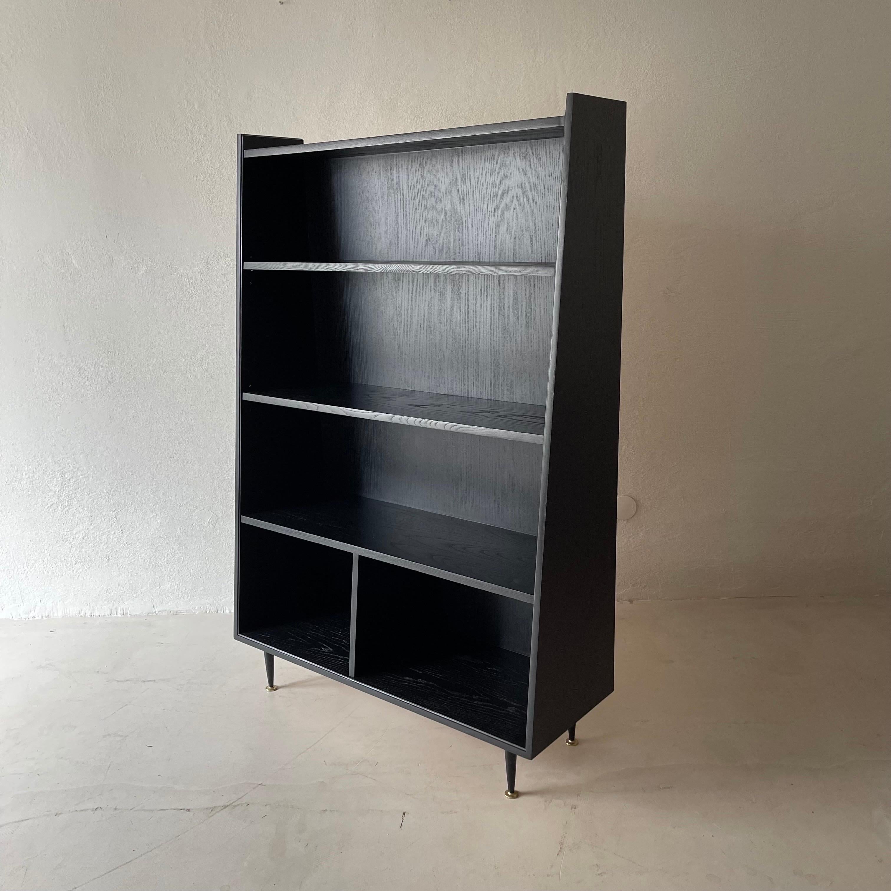Blackened bookcase shelves 1950s, standing on black metal feet with gold colored details.