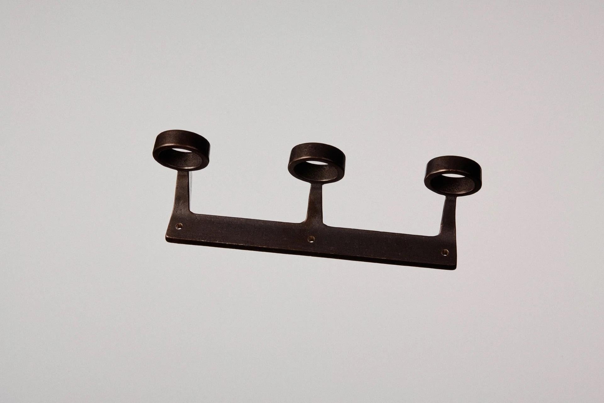 Blackened Bronze Trio Bottle Bracket by Henry Wilson
Dimensions: W 23.5 x D 7.1 x H 5.7 cm
Materials: Blackened bronze.

Available in Solo, Duo, or Trio versions.

Available in three configurations, the Bottle Bracket is designed to accommodate one,