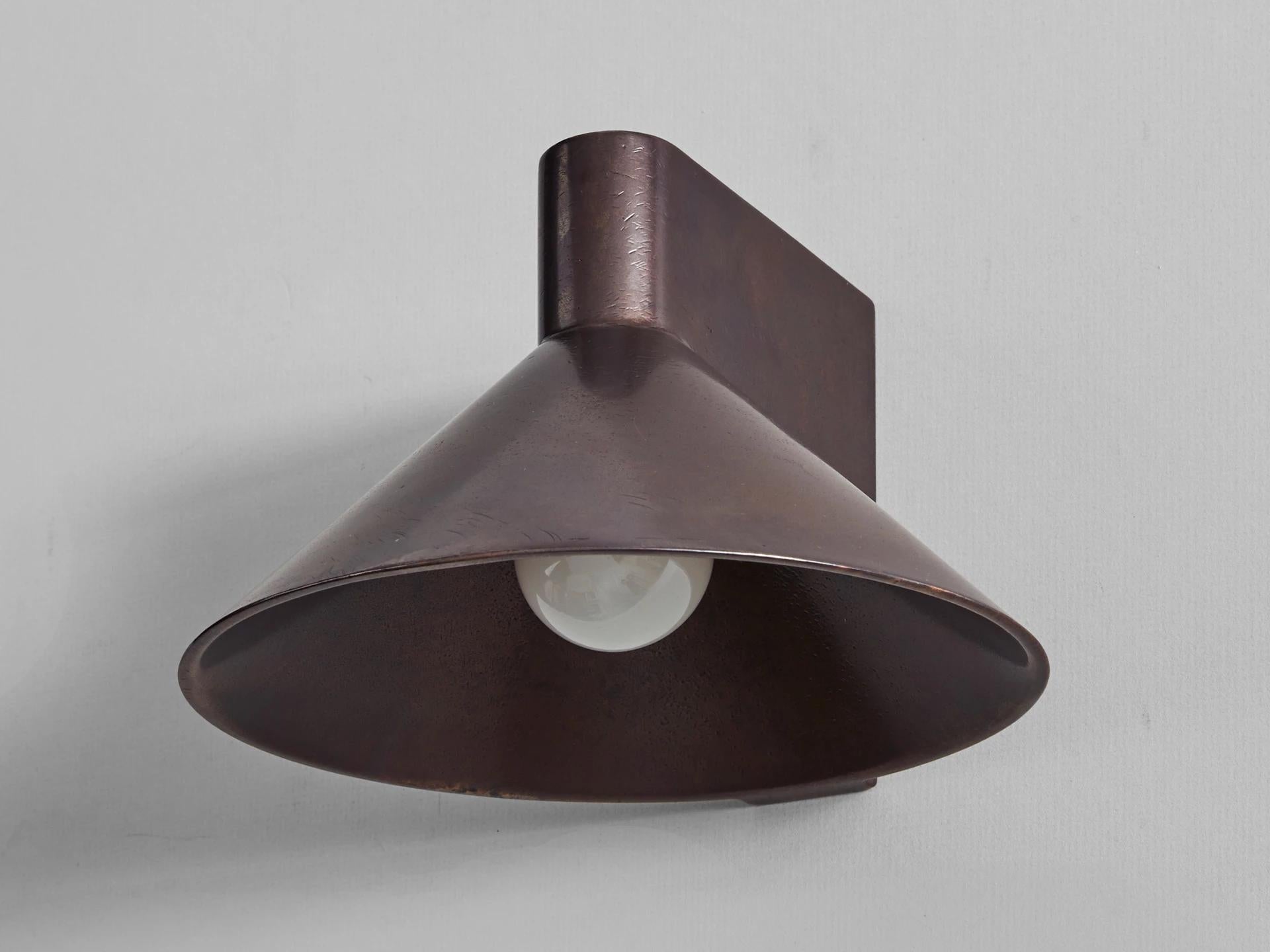 Blackened bronze wall light by Henry Wilson
Lost wax cast in solid bronze, the conical wall light is our most complex production casting to date. Each piece is hand finished and can be mounted to any surface as an up or down light, using a discrete