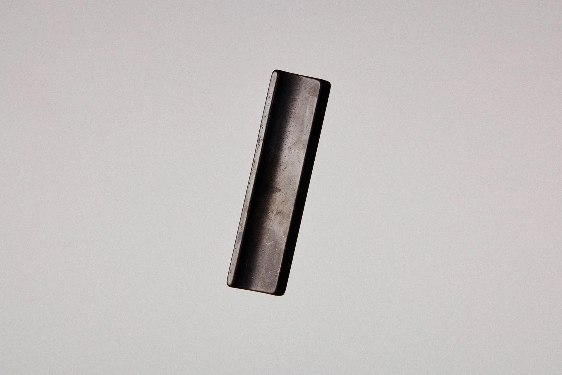 Maniglia bruta annerita di Henry Wilson
Dimensioni: L. 3 x P. 2 x H. 10 cm
Materiali: Bronzo annerito.

Questa maniglia versatile può essere utilizzata per armadi, porte scorrevoli e finestre ad anta. 
Ogni pezzo è fuso in sabbia e rifinito con