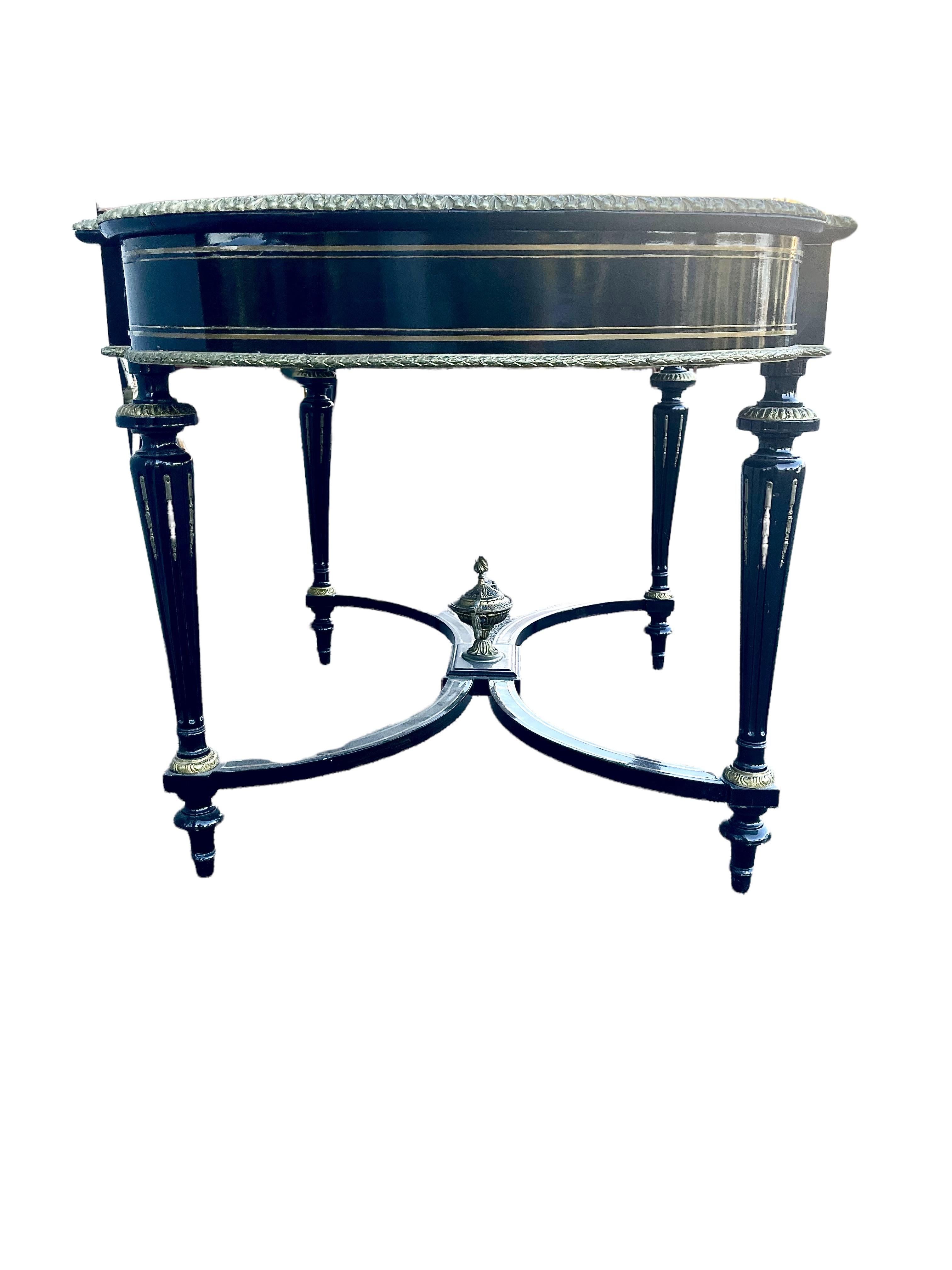 An imposing Napoleon III center table (or 'Table de Milieu') in ebonized fruit wood, rectangular in shape, with rounded sides. 
Its ornate top, which is bordered all around with a gilt bronze frieze and two further inner bands, features at its