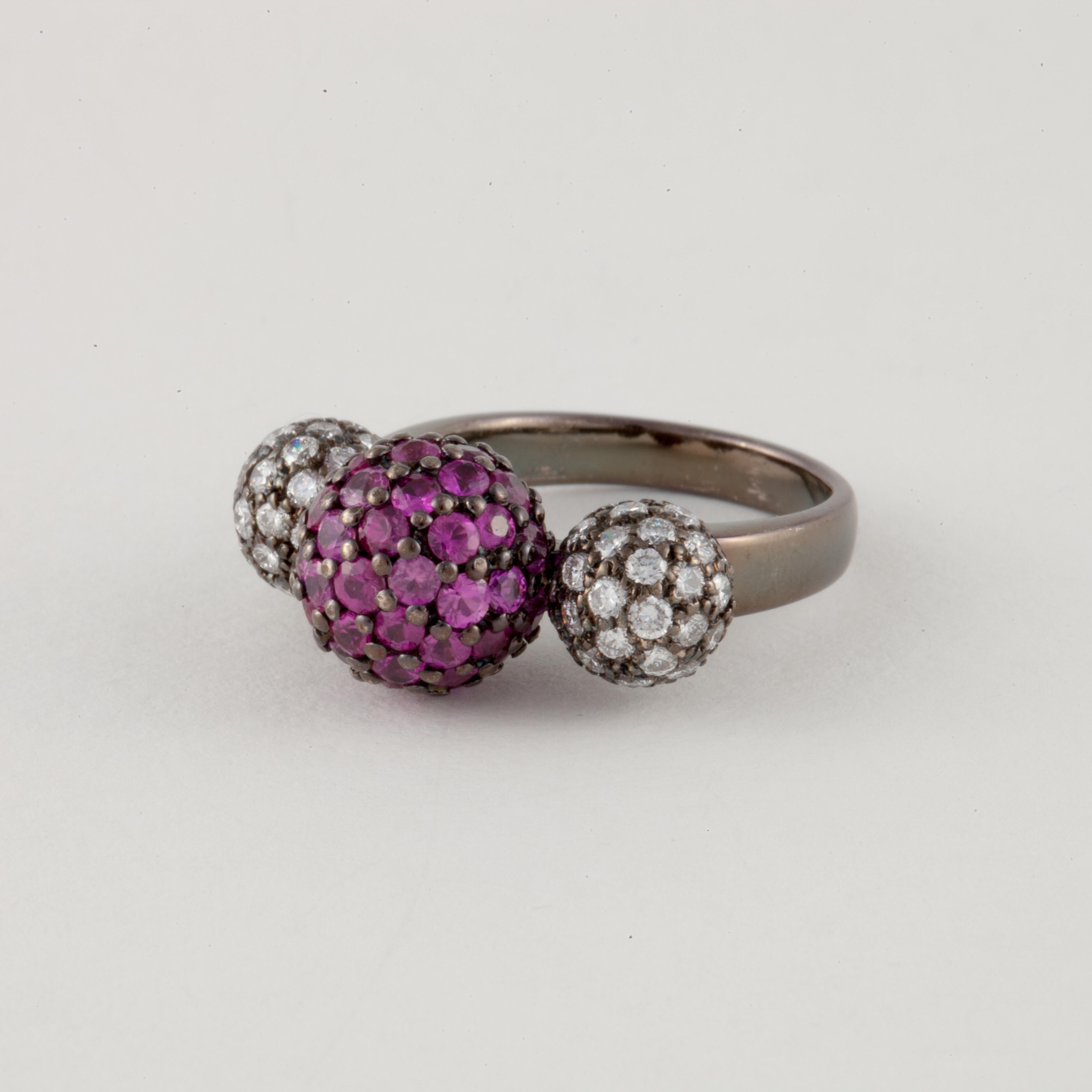Ring featuring pavé diamond and ruby balls in 18K blackened gold.  The two smaller outside balls have seventy-four round diamonds totaling 1.50 carats.  The center ball has fifty-three round rubies totaling 2.65 carats.  Presentation area measures