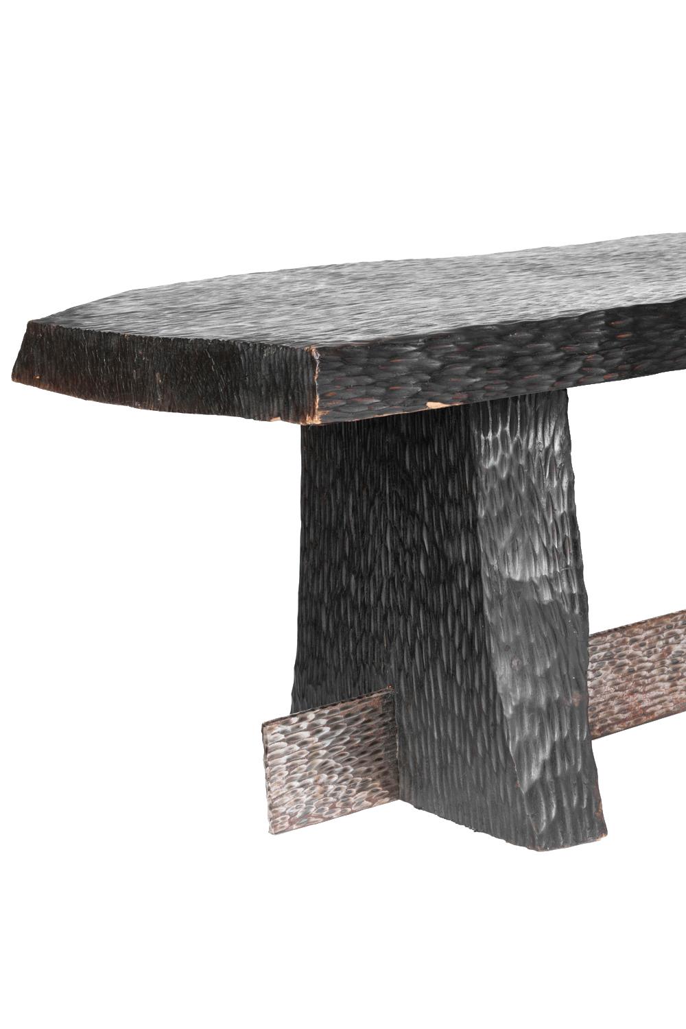 Coffee table standing on legs composed of a blackened gouged wood rectangular leg with bottom flaring and a gouged silvered metal leg with a right-angled corner forming a central stretcher.
Rectangular tray with cut edges in blackened gouged wood