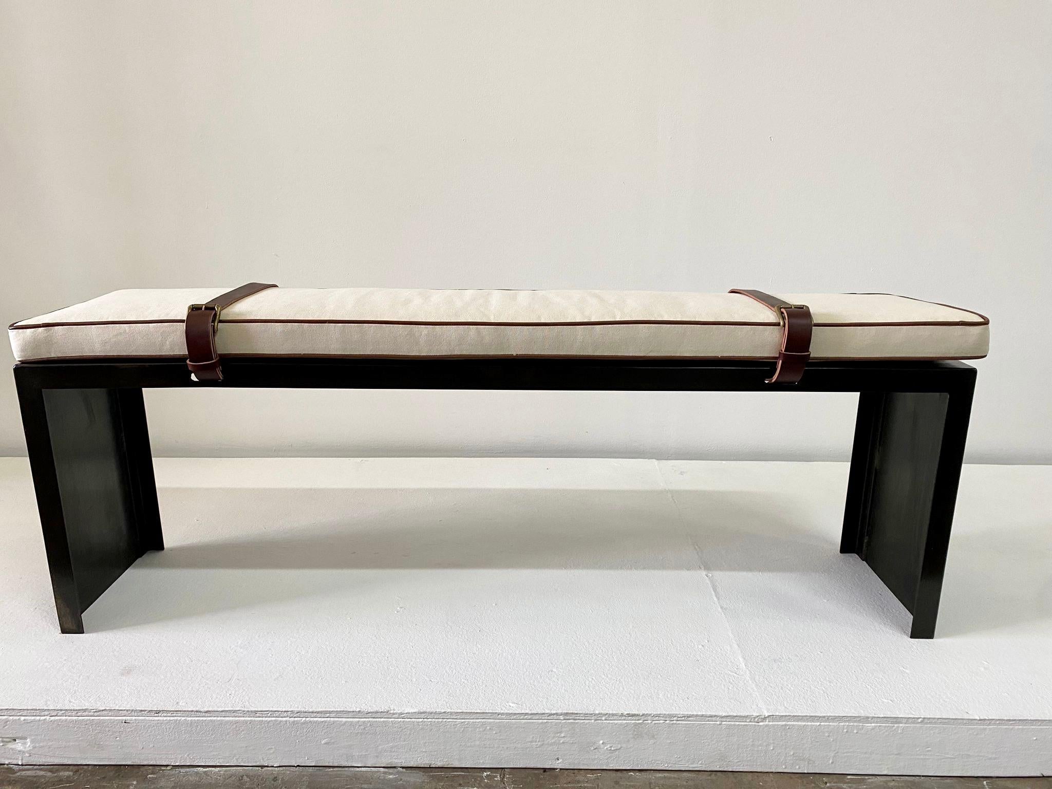 This industrial style bench with clean lines is topped by a cognac leather piping seat cushion and two cognac leather belt straps to keep it in place. This is heavy and solid, comfortable with the newly upholstered bench cushion. NOTE that height of