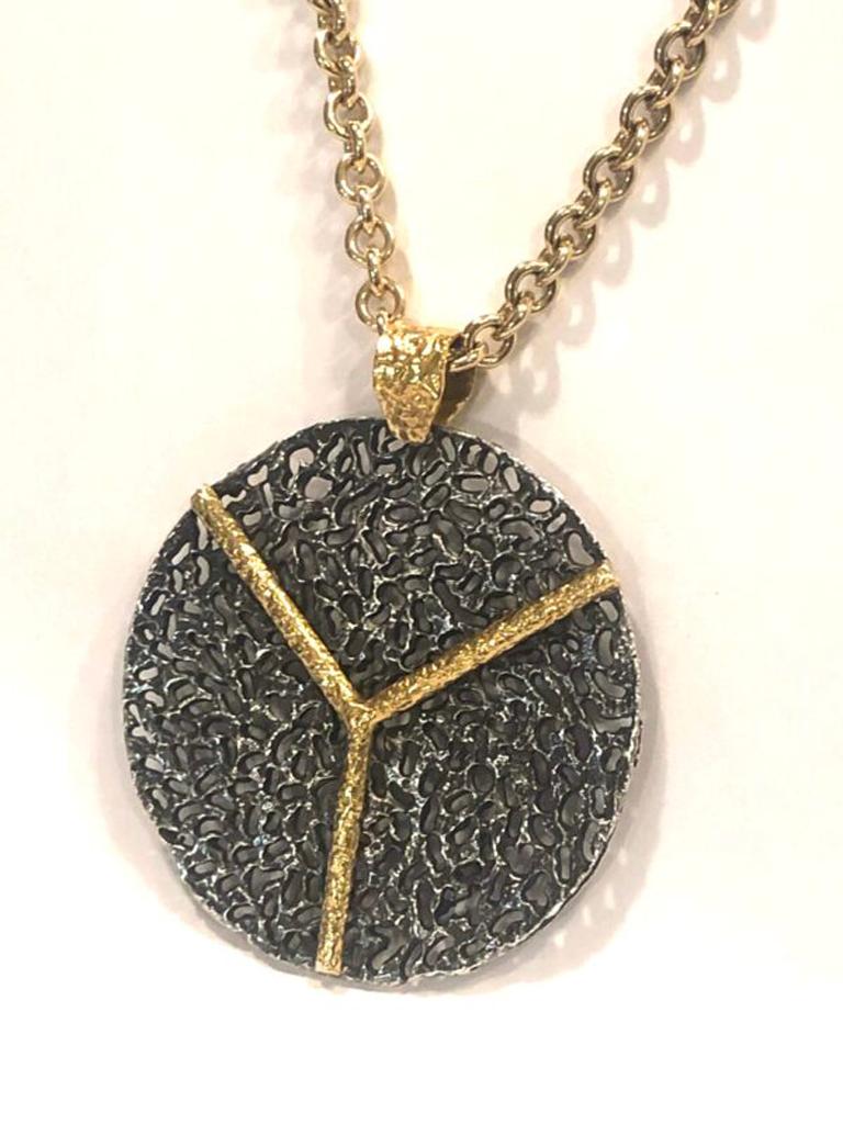 Blackened silver pendant with 22k gold accents. Mixed metals at its best! Hand carved, hand textured, edgy classic cool. Sold with an 18k gold 16″ necklace. Part of the Blackened Silver Power Collection which represents a woman beauty, uniqueness