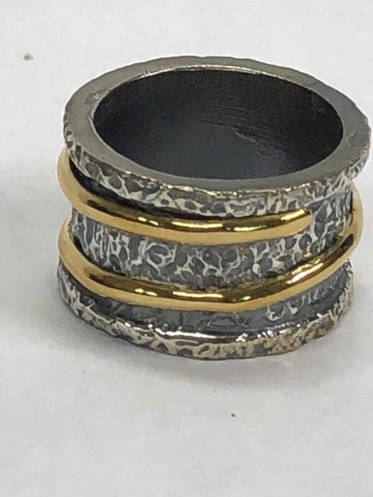 Blackened silver ring with 22k gold wraparound band, hand textured, hand carved, edgy cool classic. Part of the Power Collection which signifies a woman beauty, uniqueness and power. 

The Tagili Promise: With every piece sold a portion of the