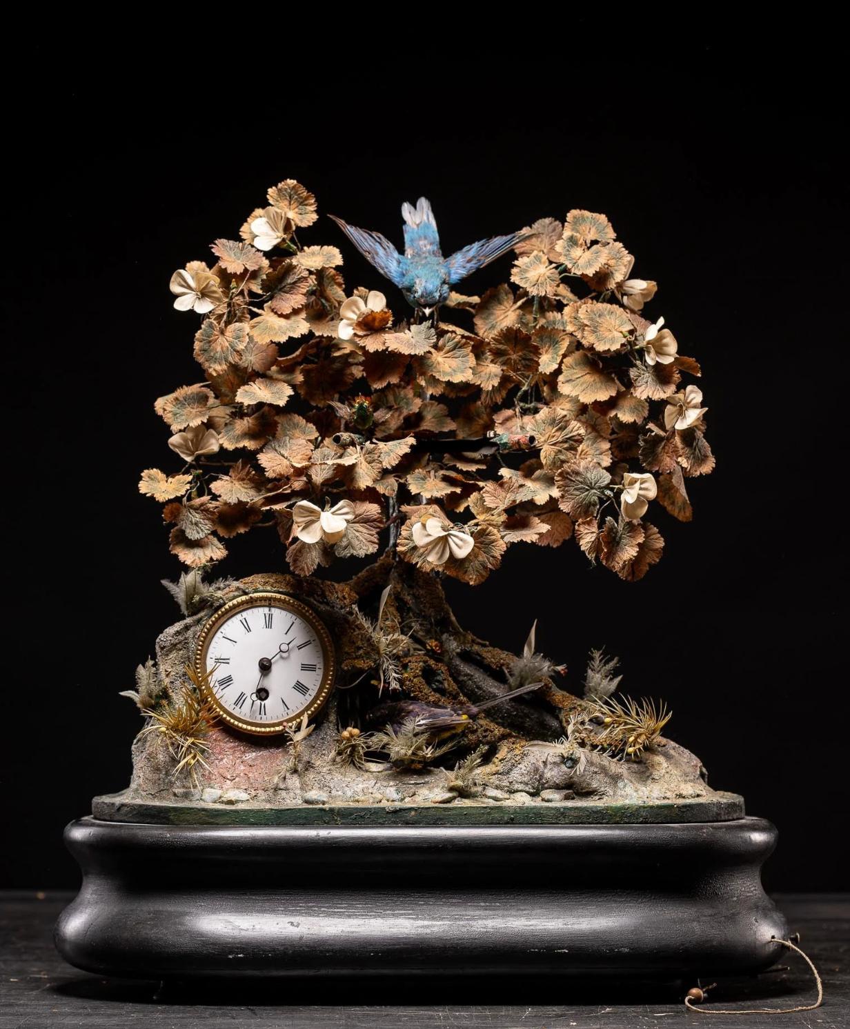 This 19th-century French automaton from the late 1800s showcases a delightful ensemble of features: three vibrant animated birds, a cascading waterfall, a tree surrounded by rocky outcrops and foliage, a tranquil pond, and a clock. Concealed within