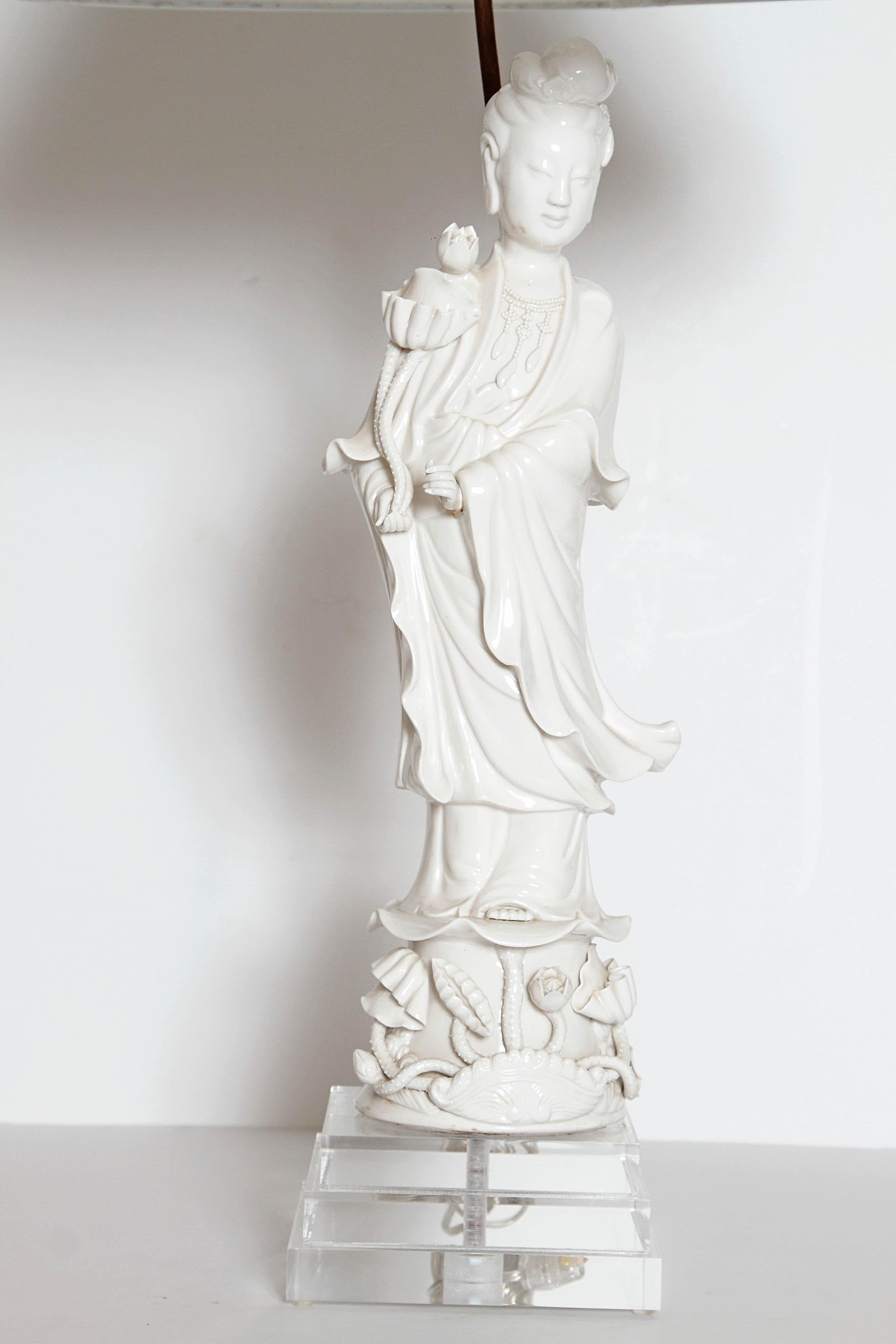 A large Chinese porcelain figure of Guayin with exquisite fine detail. The deity is depicted standing wearing flowing robes, holding a lotus flower in one hand standing on an embellished pedestal base consisting of a floating lotus lead above buds