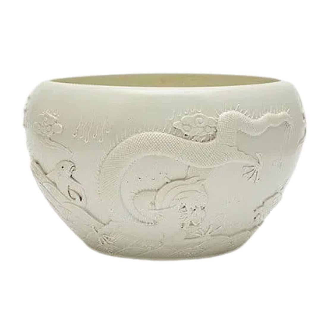 Exemple raffiné d'un savoir-faire de qualité, ce lave-brosse en porcelaine à pâte tendre présente une glaçure blanche lumineuse et porte la marque Qianlong. La forme peu profonde du bol est accentuée par un motif de dragon en relief, gracieusement