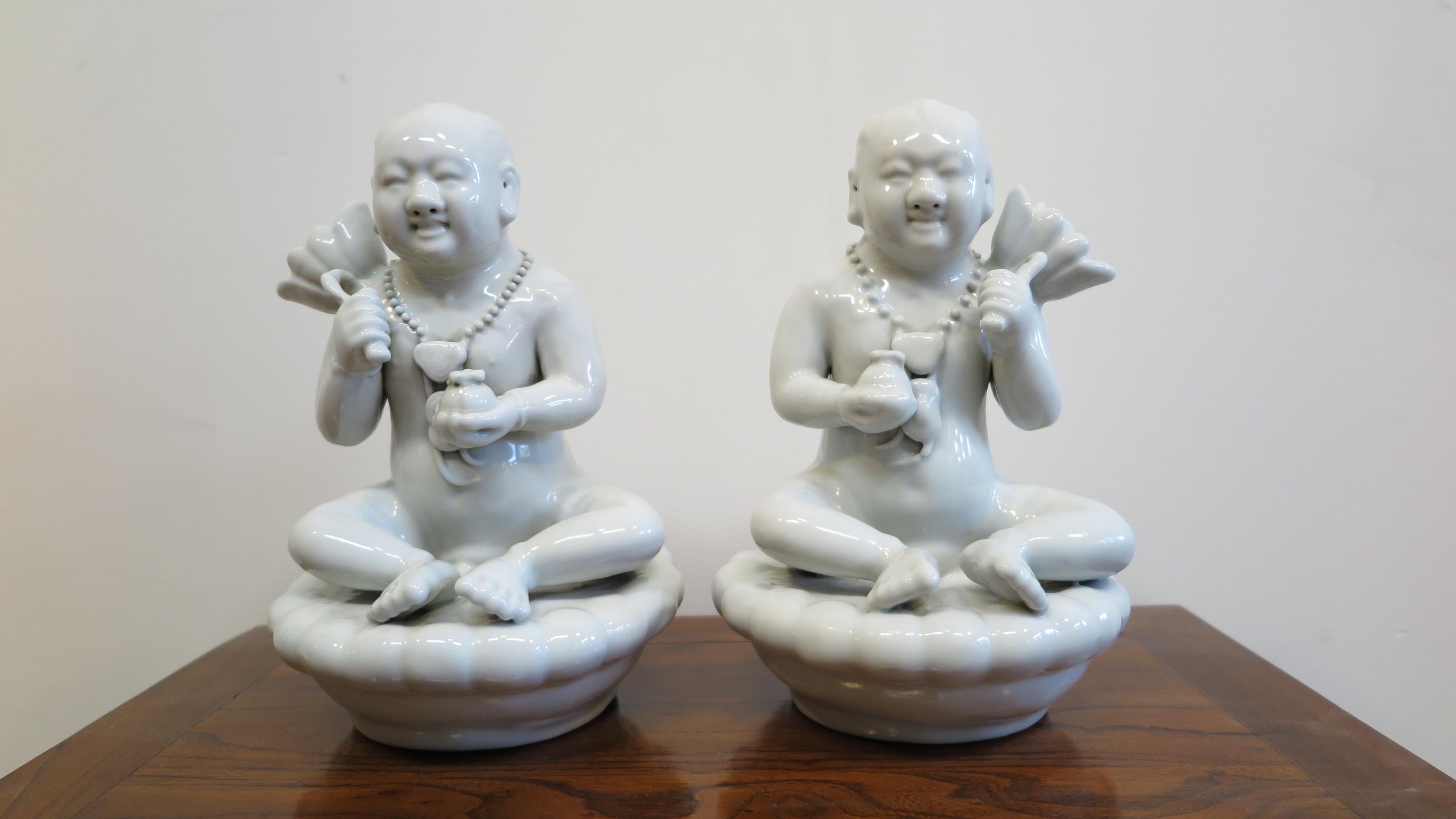 Pair of Blanc De Chine porcelain Chinese money children. A left and right sided pair of Blanc De Chine figures also known as Sudhana (Children of Wealth) Wealth deity. Having both a left and right sided set each piece having differences between them