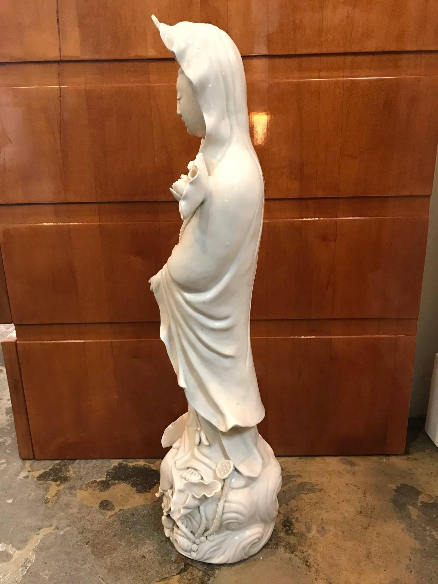 Porcelain Quan Yin figure standing with flowers. Qing dynasty. Kangxi period.