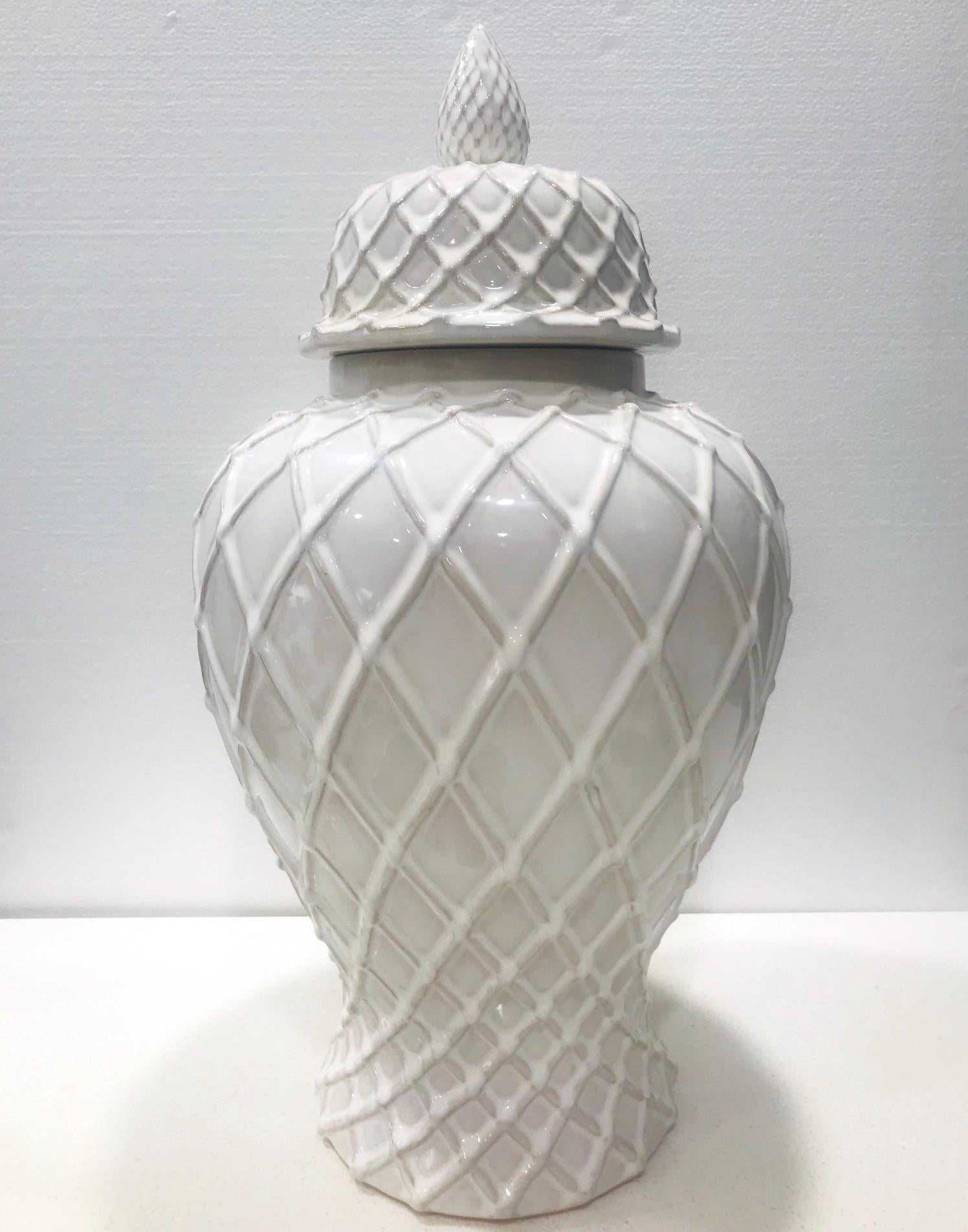 Hollywood Regency large blanc de chine lidded ginger jar with a white glaze finish. Handmade pottery vase has the form of an urn with Chippendale style lattice designs throughout. The jar features a tapered base while the lid is adorned with a