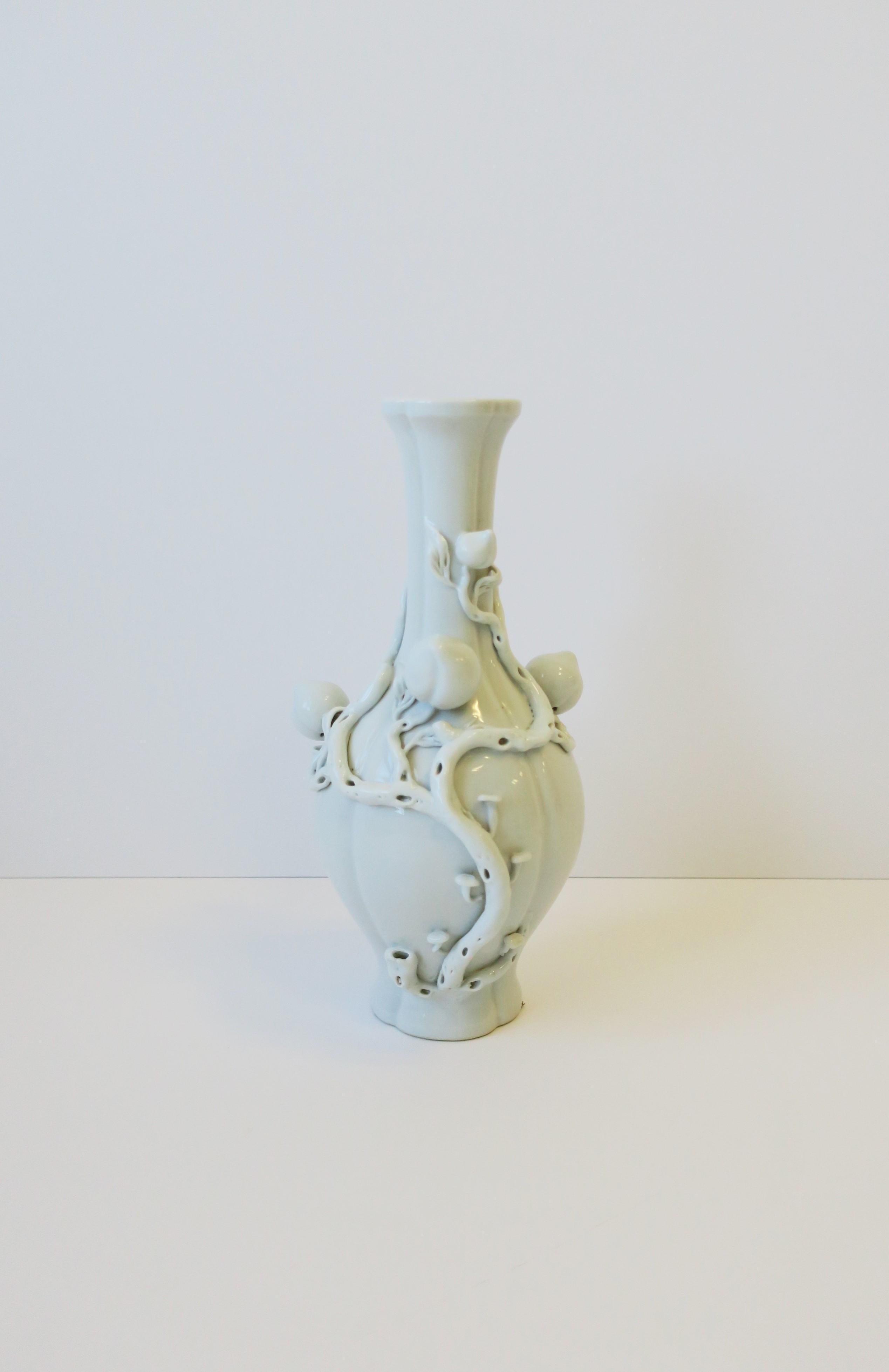 A beautiful Blanc de Chine white ceramic porcelain vase with a generous relief of fruit (peaches), leaves and vines, circa 20th century, China. Dimensions: 6.5
