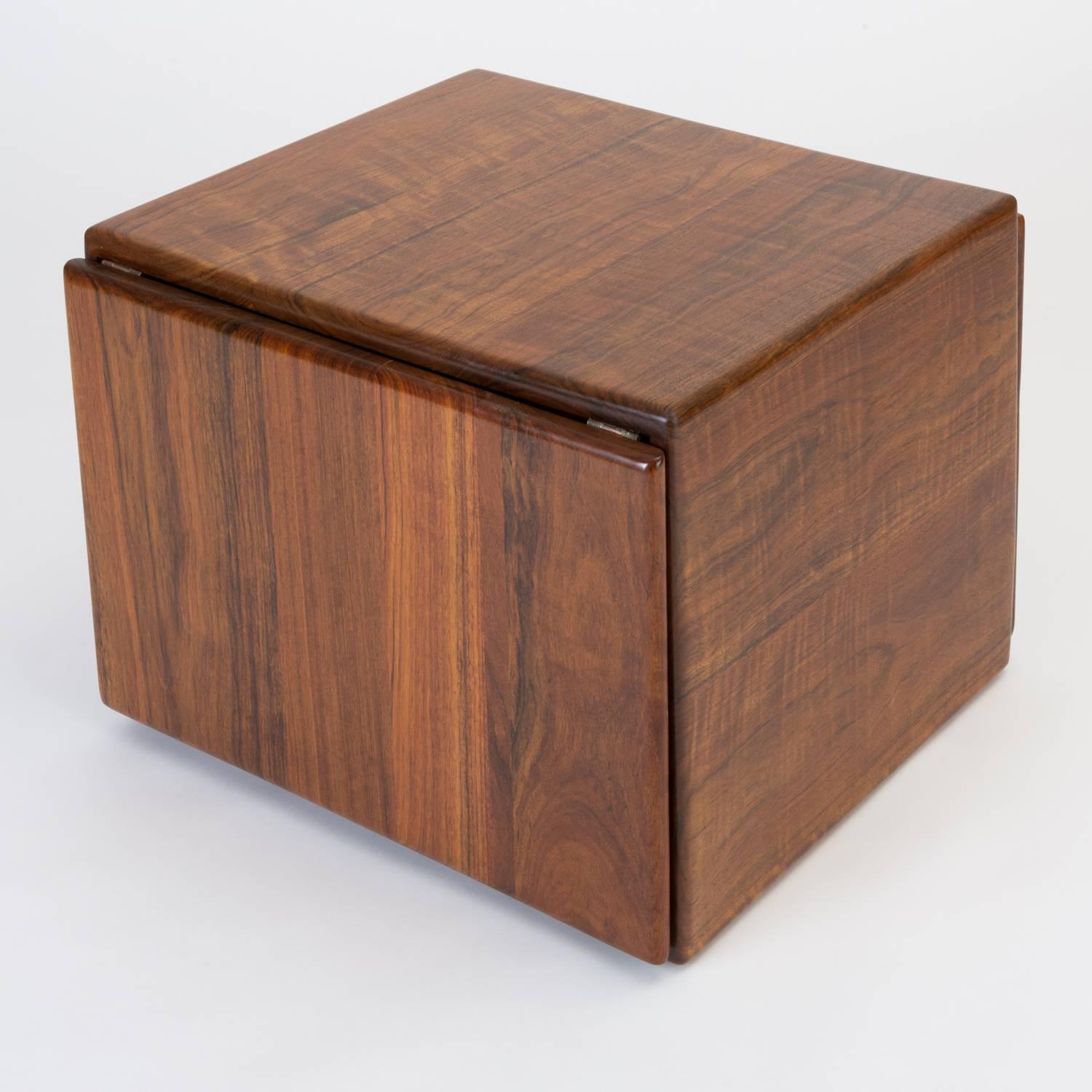 A storage cube side table, blanket box or storage chest designed and made by Gerald McCabe. McCabe, a Southern California woodworker produced this piece in lustrous shedua wood for his company, Erin Furniture. The cube has four smooth faces in solid