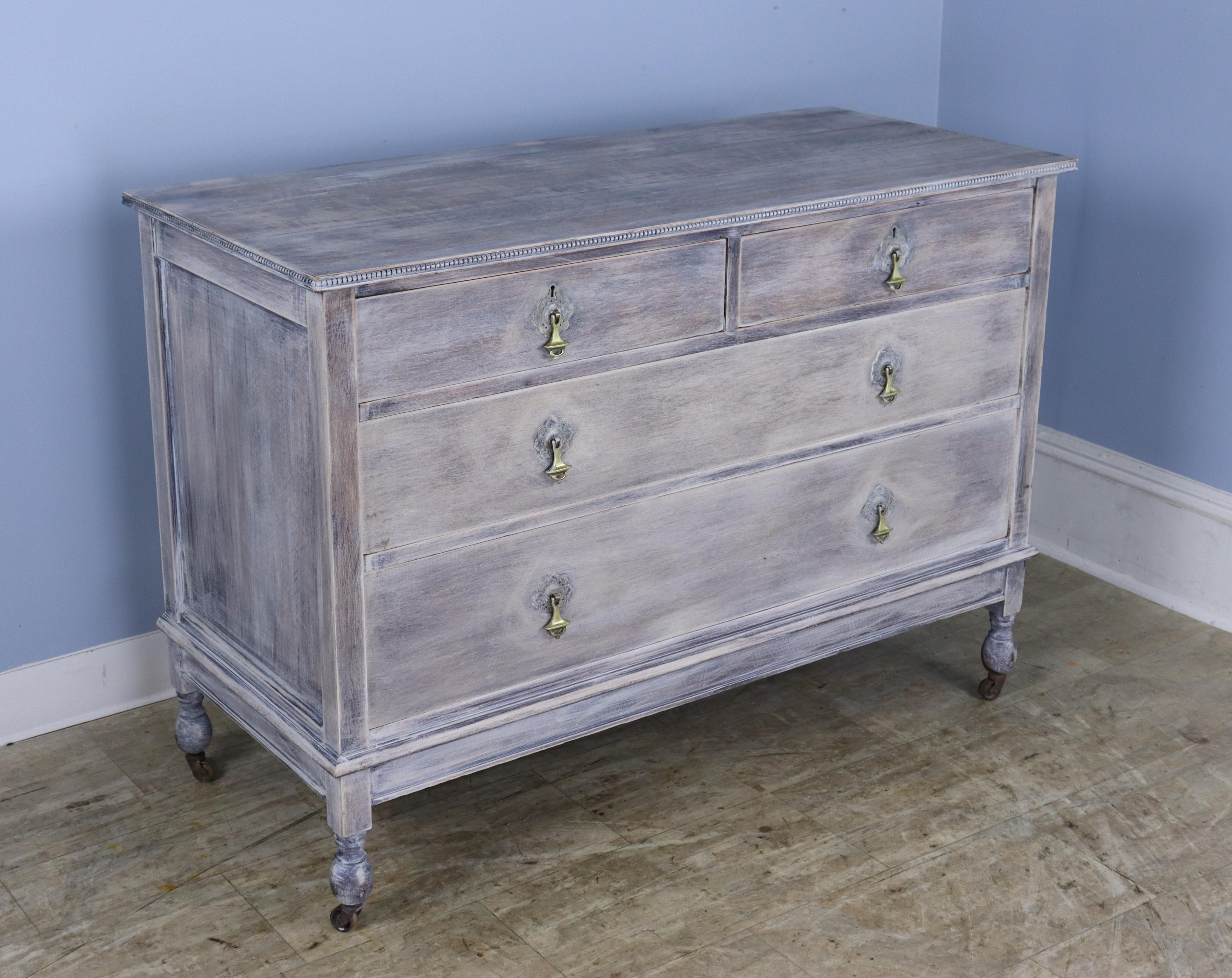 A simple and handsome commode or chest of drawers in the Directoire style, bleached and newly painted very stylishly with notes of gray, blue and russet.  The original drop handles have been polished for a glamourous pop of lightness, and the