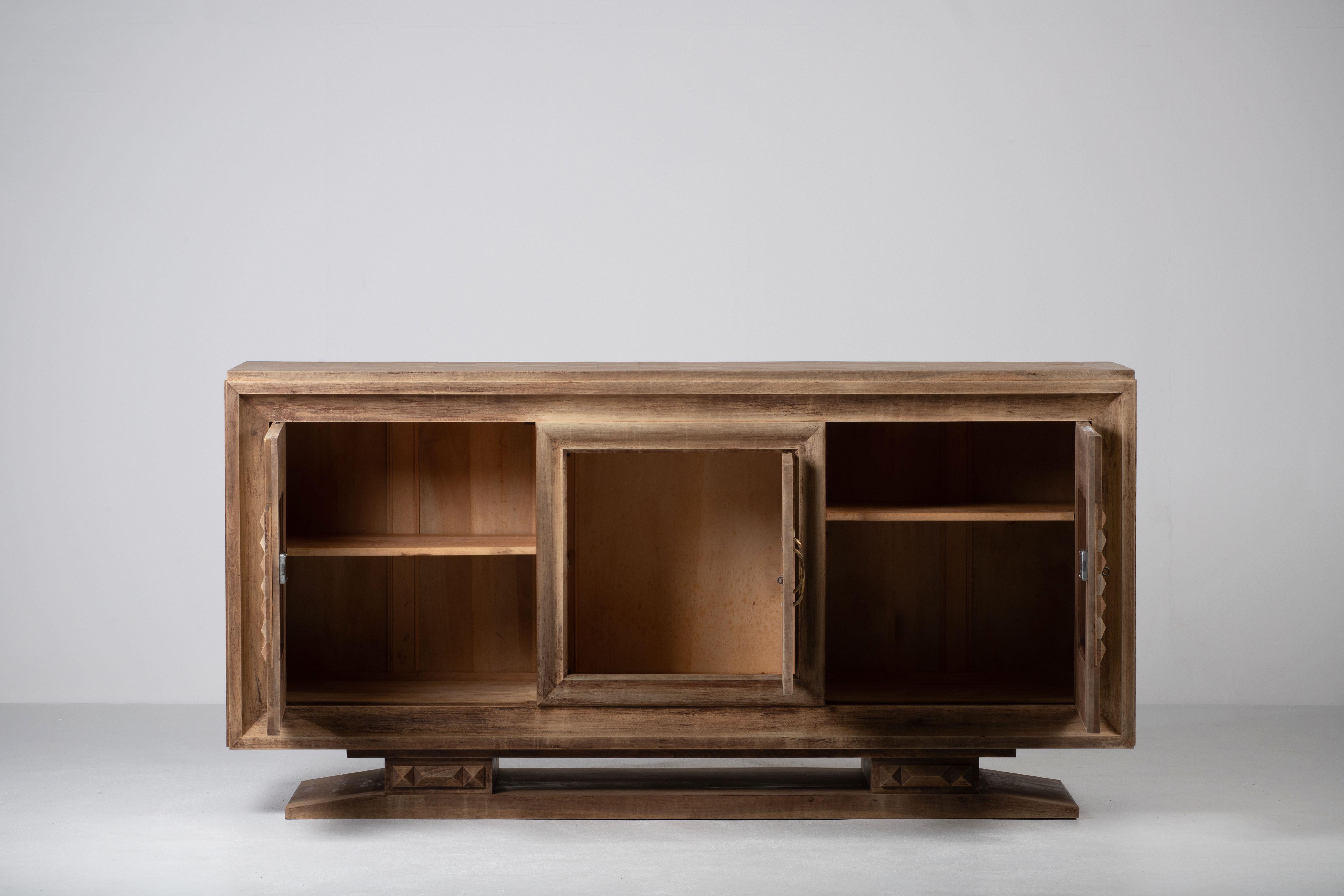 Credenza, solid oak, France, 1940s, after Charles Dudouyt.
Large Art Deco Brutalist sideboard. 
The credenza consists of three storage facilities and covered with very detailed designed door panels. 
The refined wooden structures on the doors